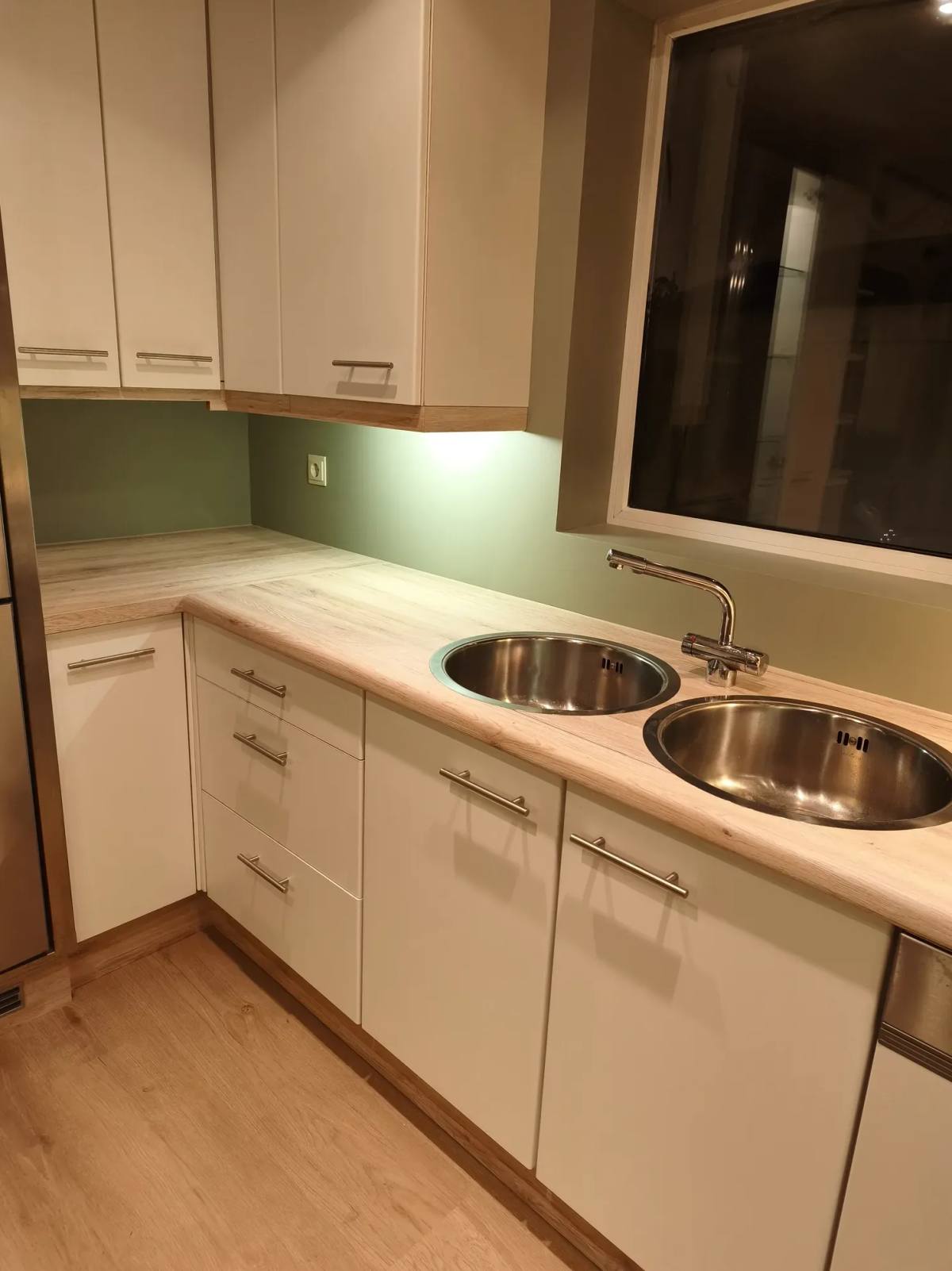Keuken met een olijfgroene achterwand en een houten tafelblad