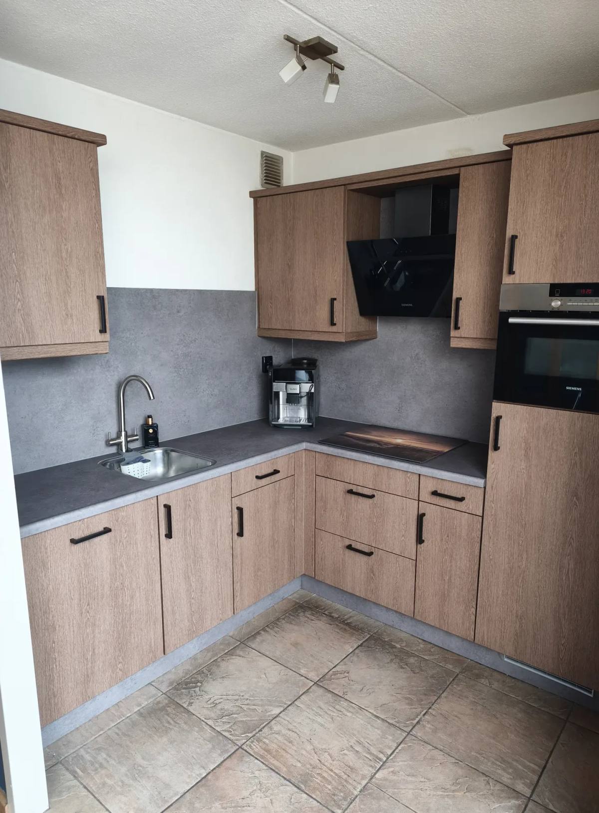 Keuken met frontjes in houtlook en een achterwand in betonlook