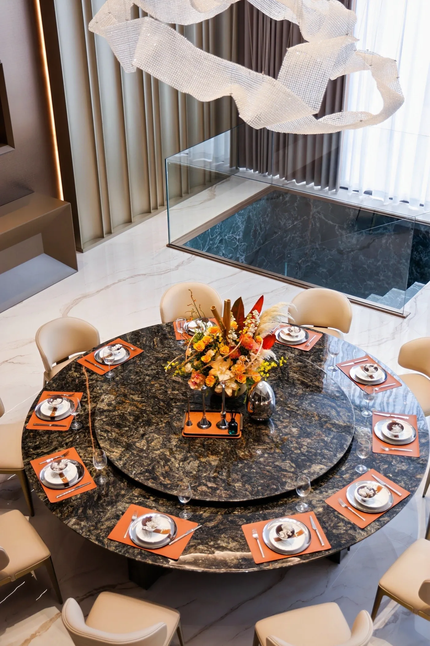 Round dining-table setting viewed from above with a stone surface and upholstered chairs.