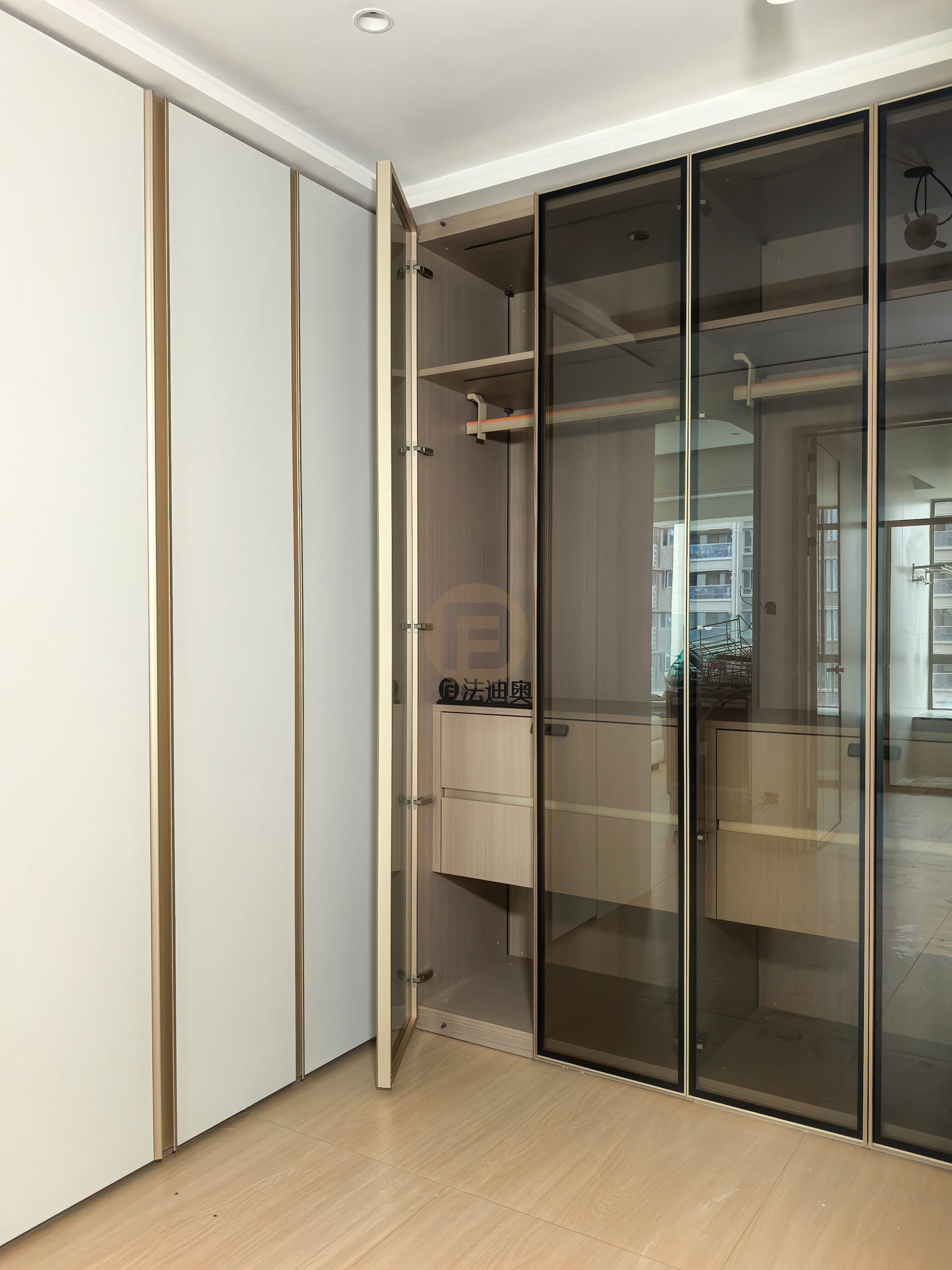 Corner wardrobe with champagne interior shelving and smoked bronze glass doors reflecting the window