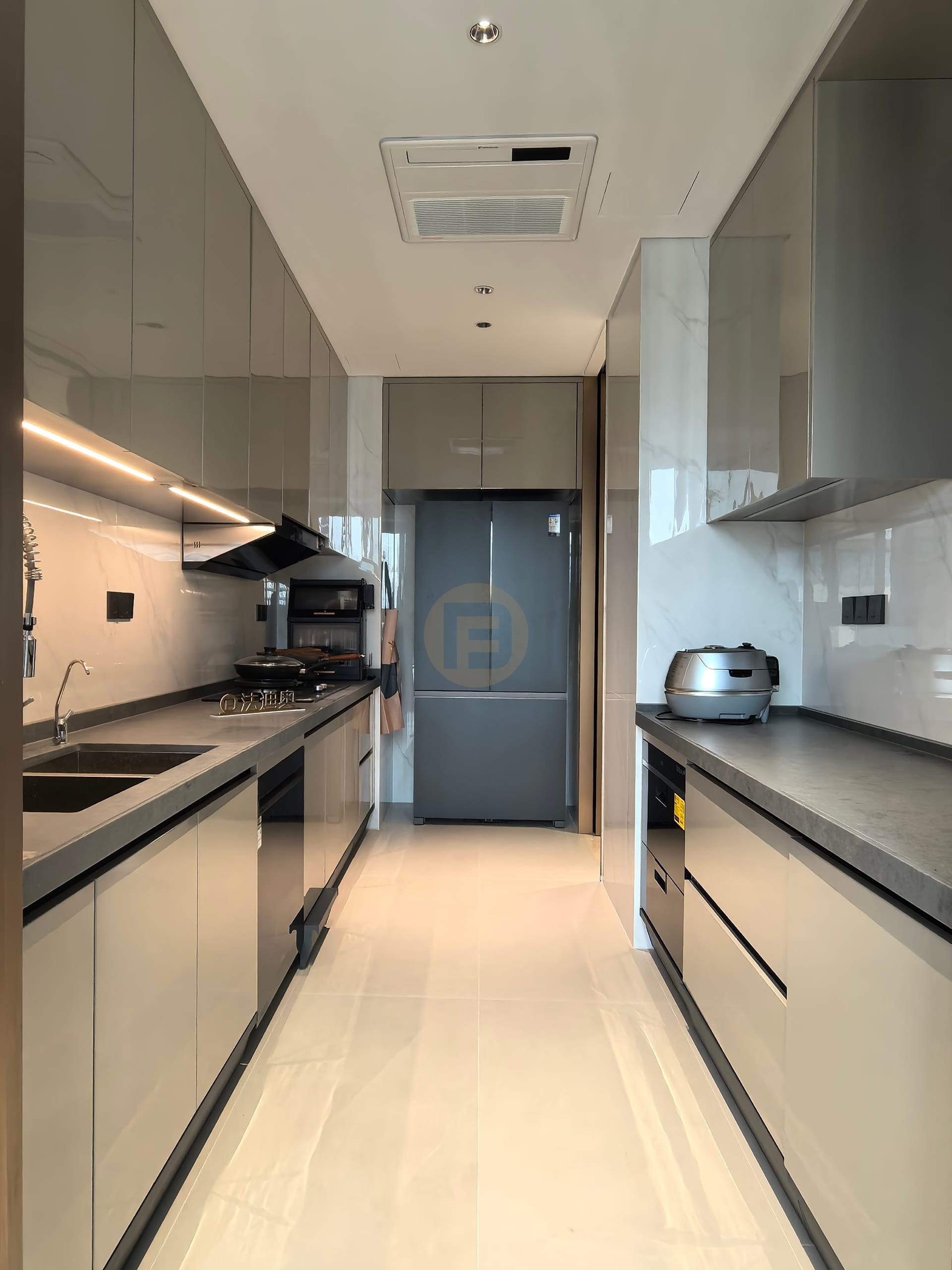 Champagne galley kitchen with dark stone worktops, full-height storage and an integrated refrigerator