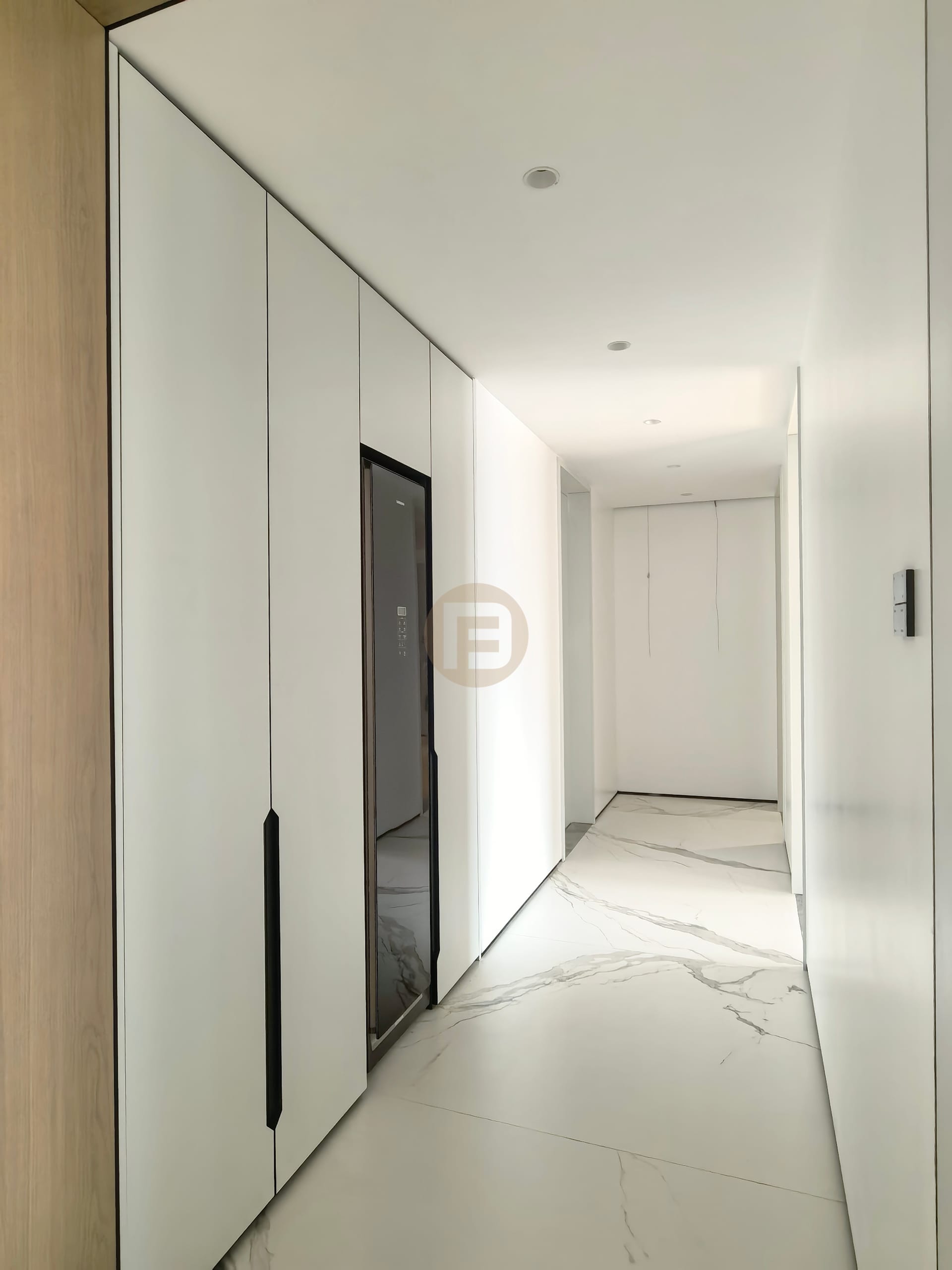 White hallway wardrobes with integrated full-length mirror over book-matched marble flooring