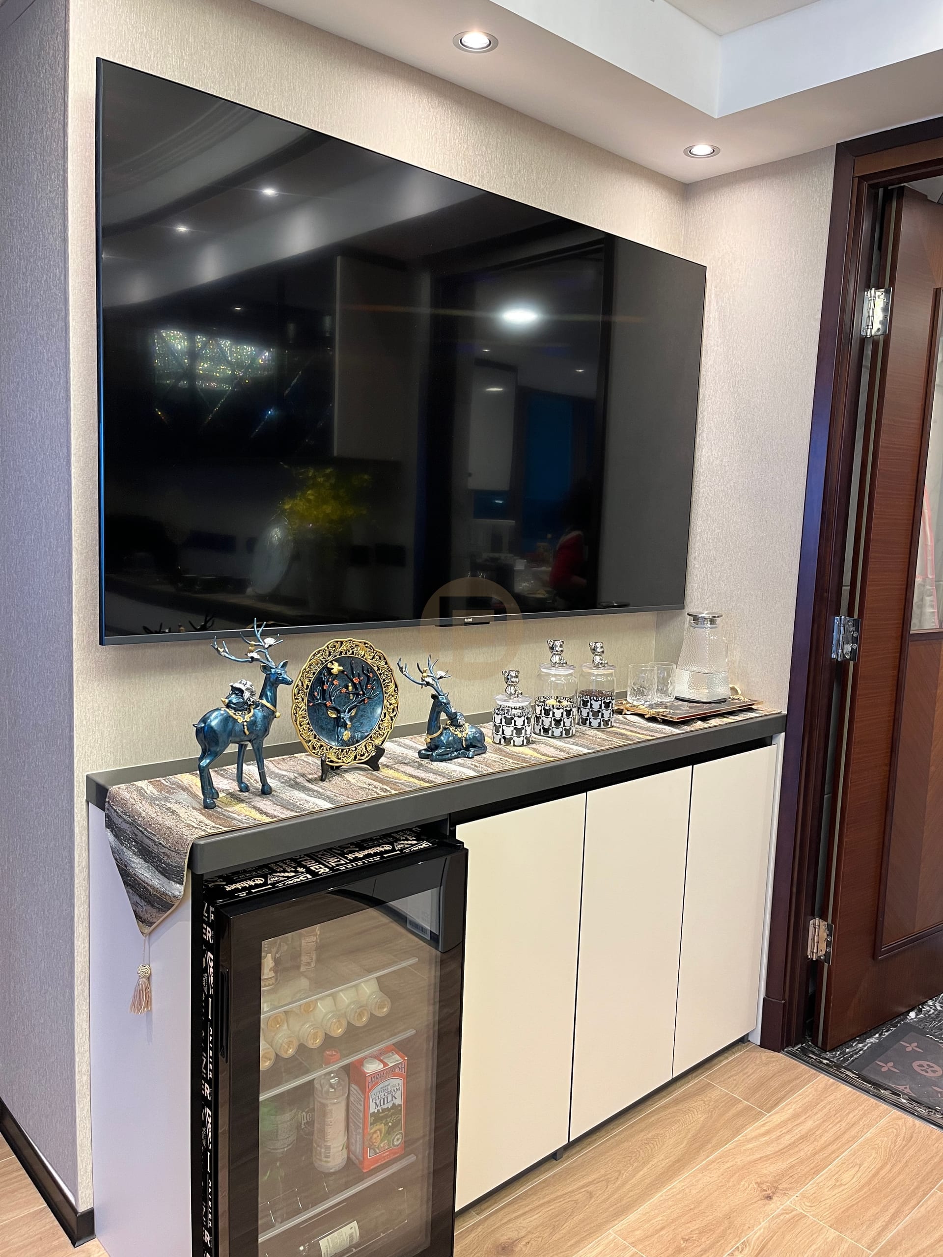 Television wall with low stainless steel cabinet integrating a glazed beverage cooler