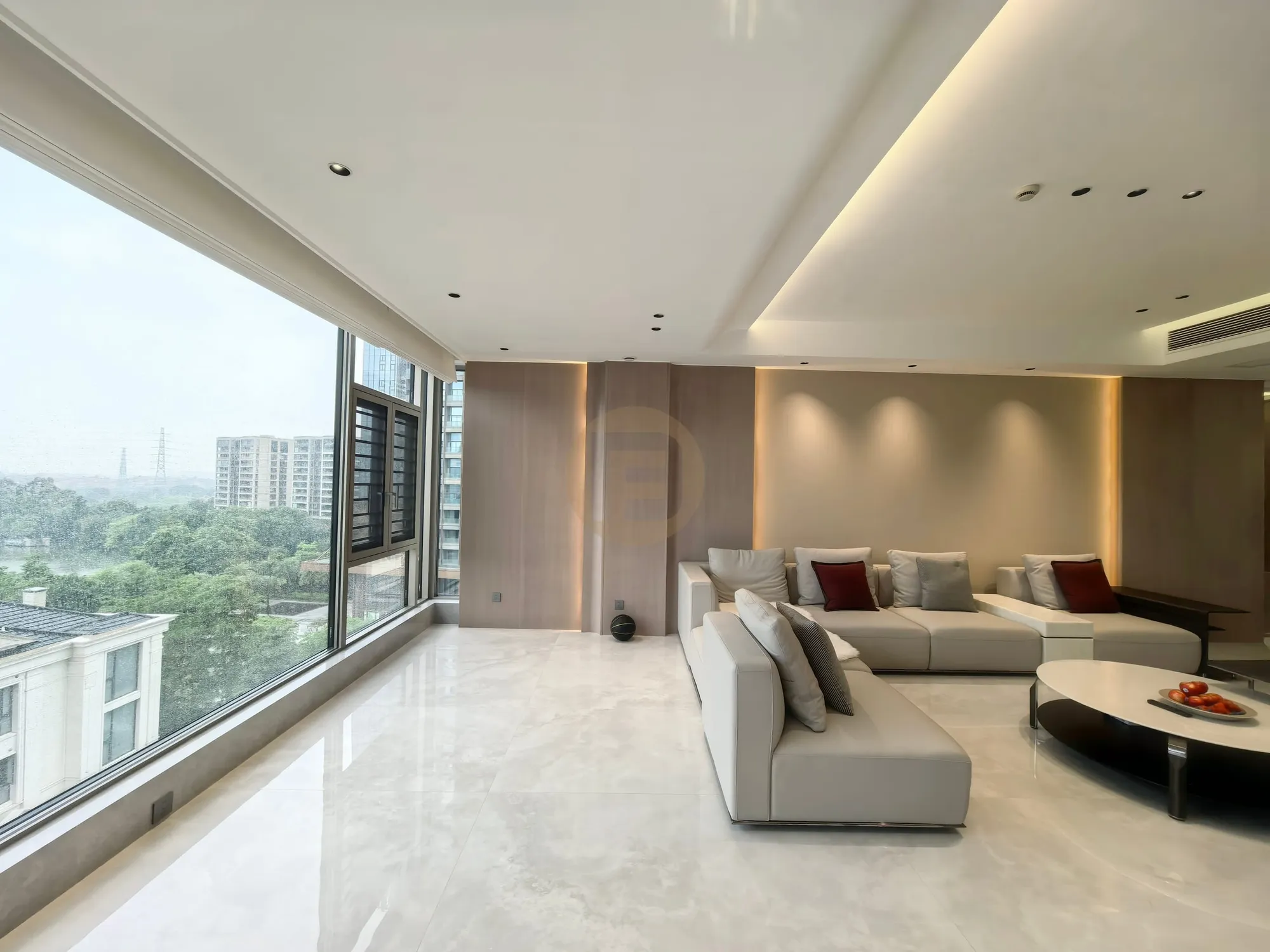 Open-plan living room with cream sofas, book-matched pale marble floor and a full wall of glazing