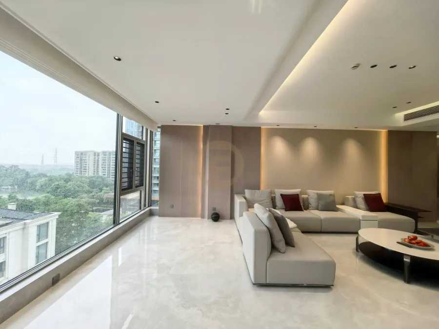 Open-plan living room with cream sofas, book-matched pale marble floor and a full wall of glazing