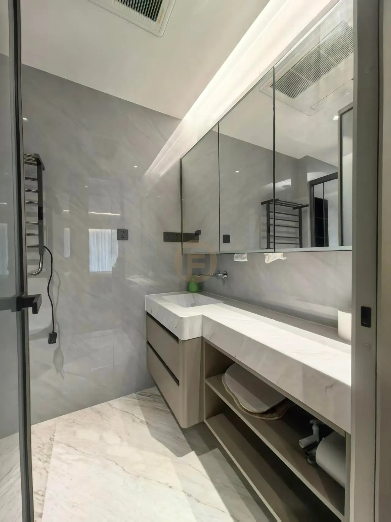 Marble-topped stainless steel bathroom vanity with mirrored cabinet and open towel shelf in a grey marble bathroom