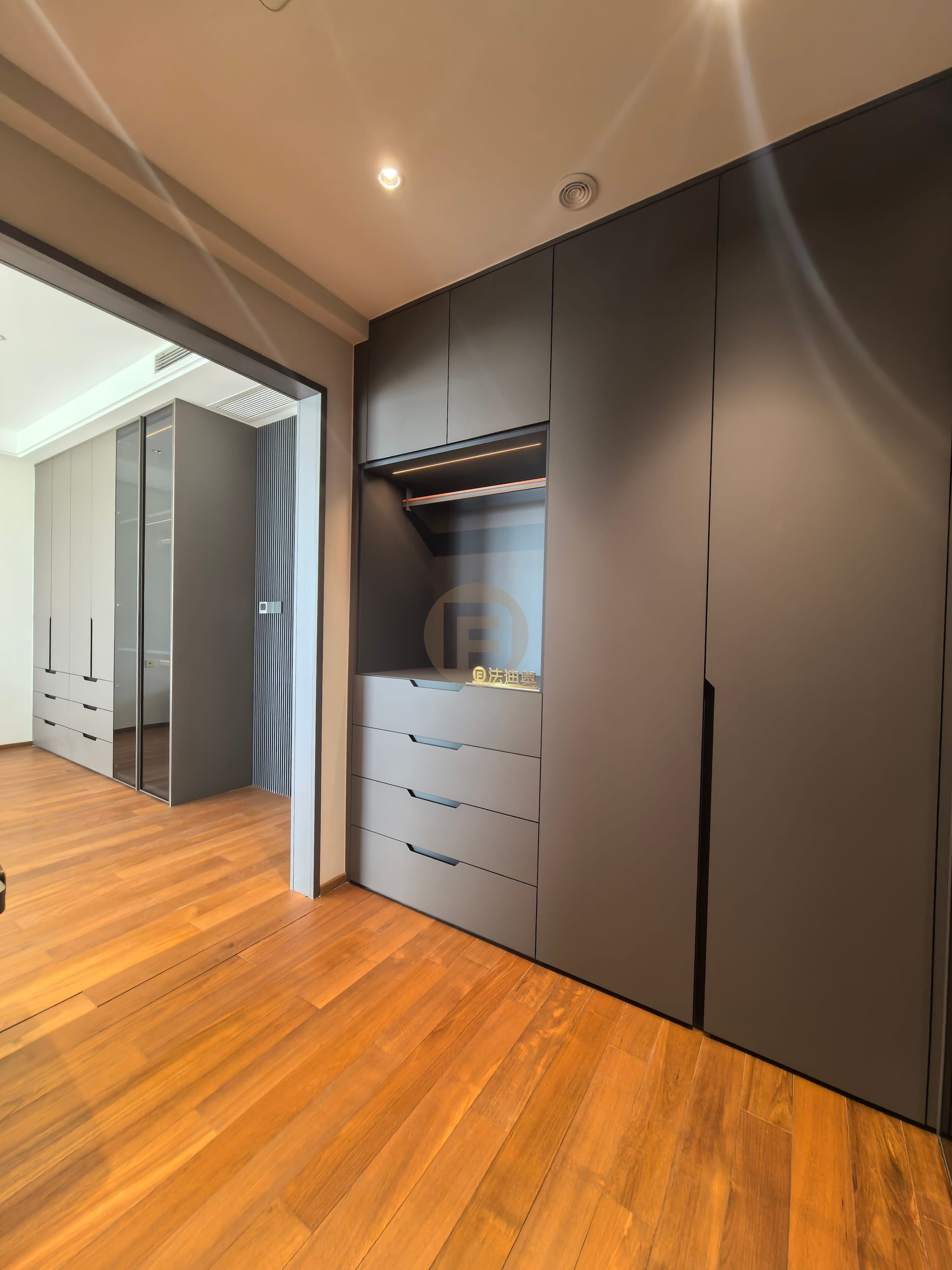 Charcoal wardrobe with open dressing niche and drawers, looking through to a second bedroom suite