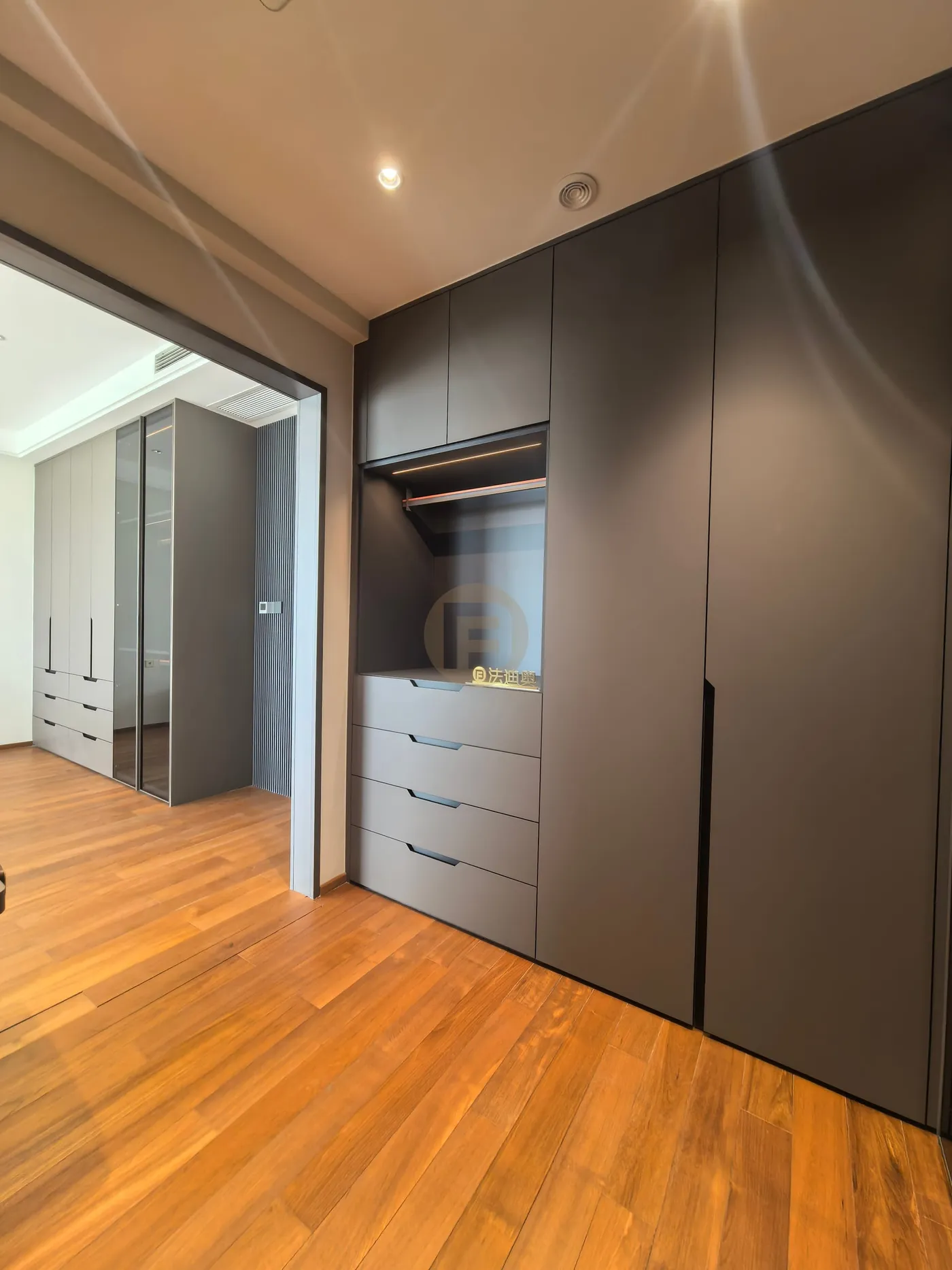 Charcoal wardrobe with open dressing niche and drawers, looking through to a second bedroom suite