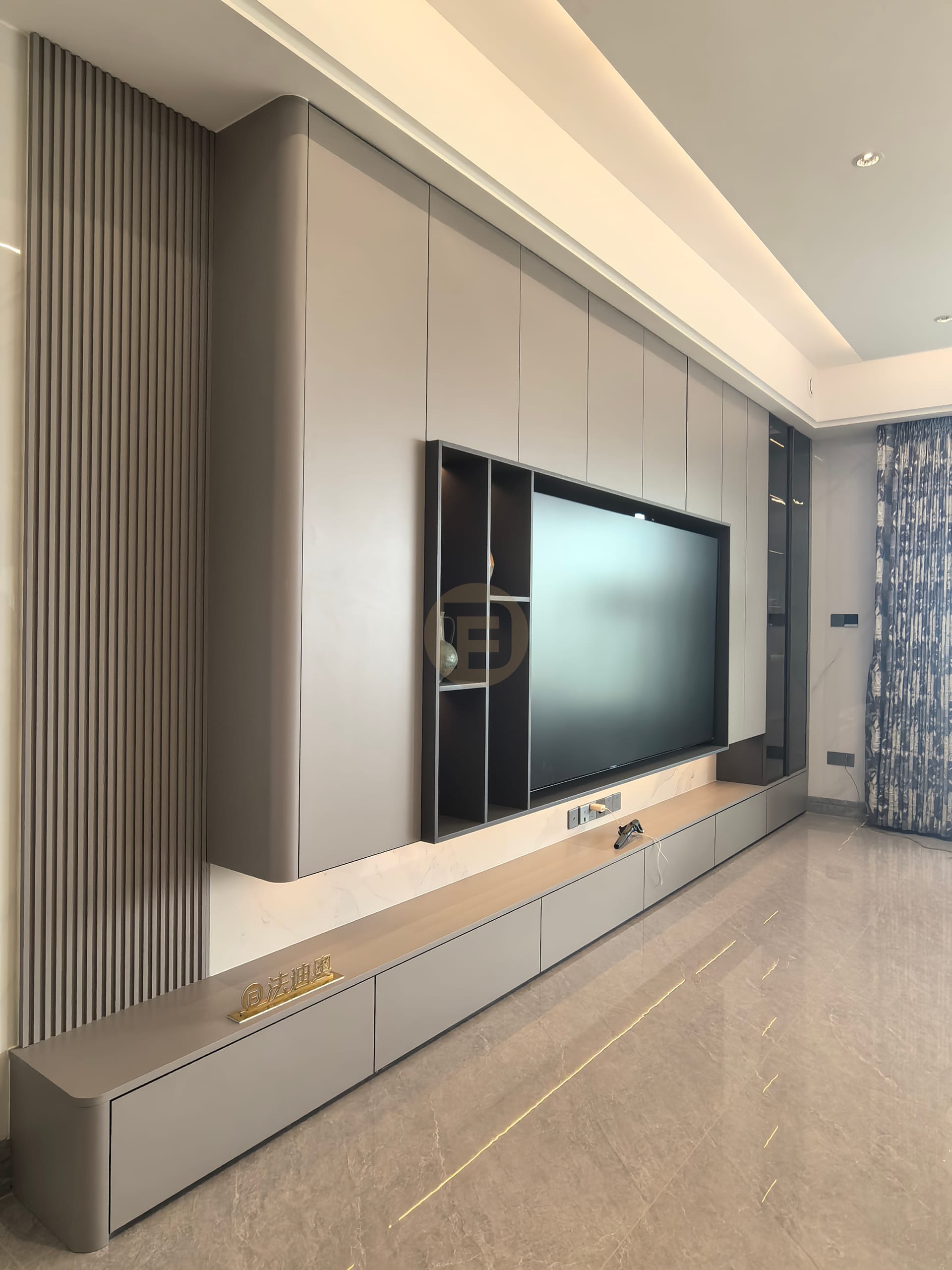Living room media wall in taupe stainless steel cabinetry with fluted panelling and recessed TV niche