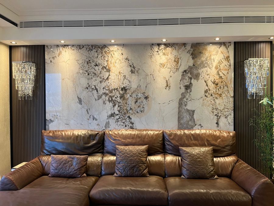 Living room with book-matched stone feature wall, fluted dark panels, crystal sconces and leather seating