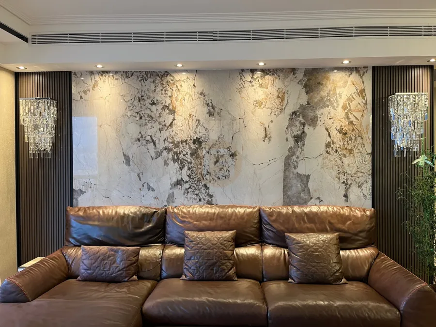Living room with book-matched stone feature wall, fluted dark panels, crystal sconces and leather seating