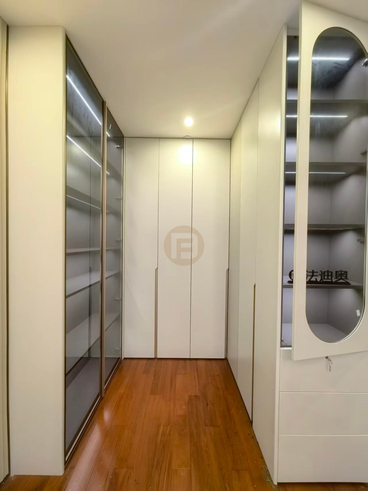 Walk-in closet corridor with bronze-framed smoked-glass wardrobes and cream stainless steel cabinetry