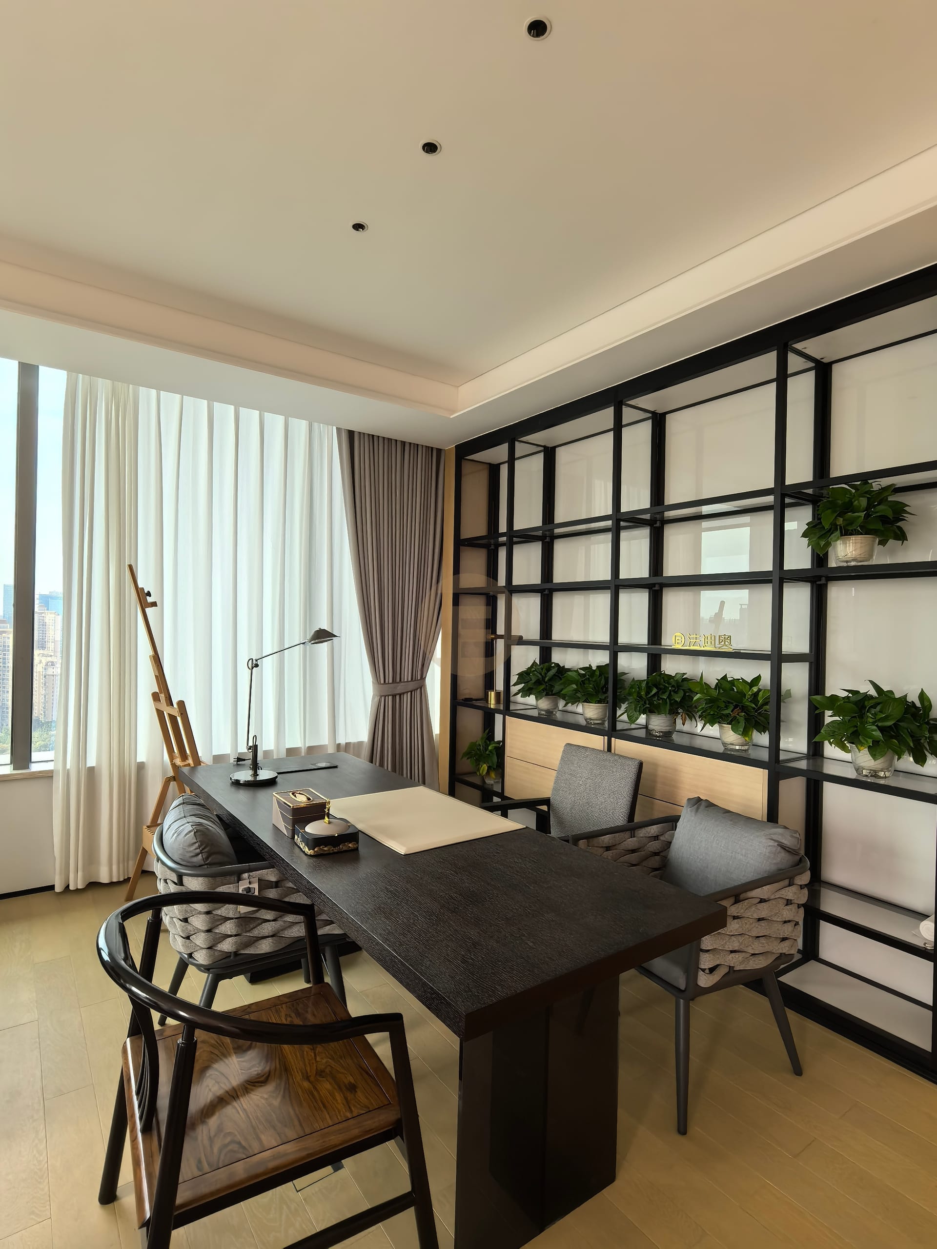 Study with black steel display shelving, a dark writing desk and full-height curtains at the corner window