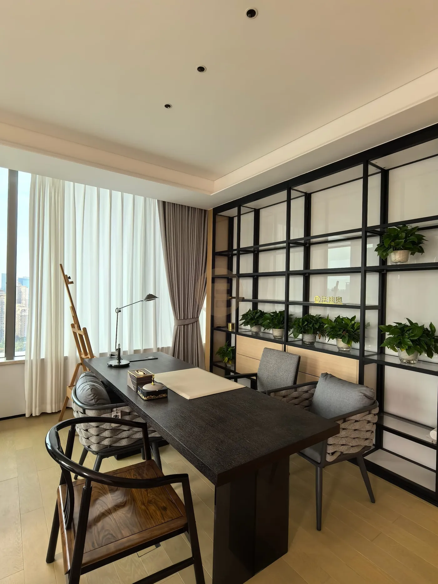 Study with black steel display shelving, a dark writing desk and full-height curtains at the corner window