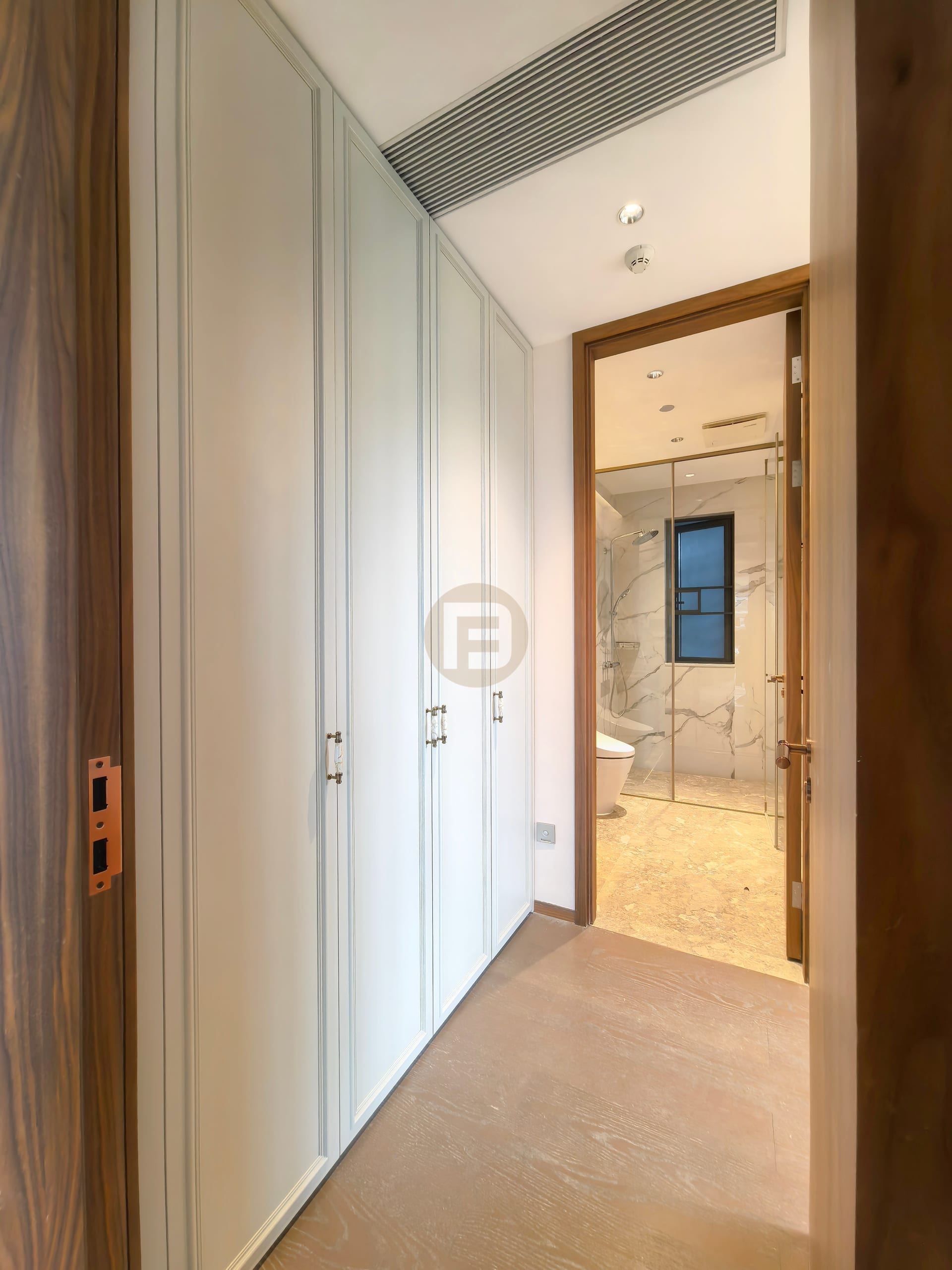 Wardrobe-lined corridor leading into a marble-clad bathroom