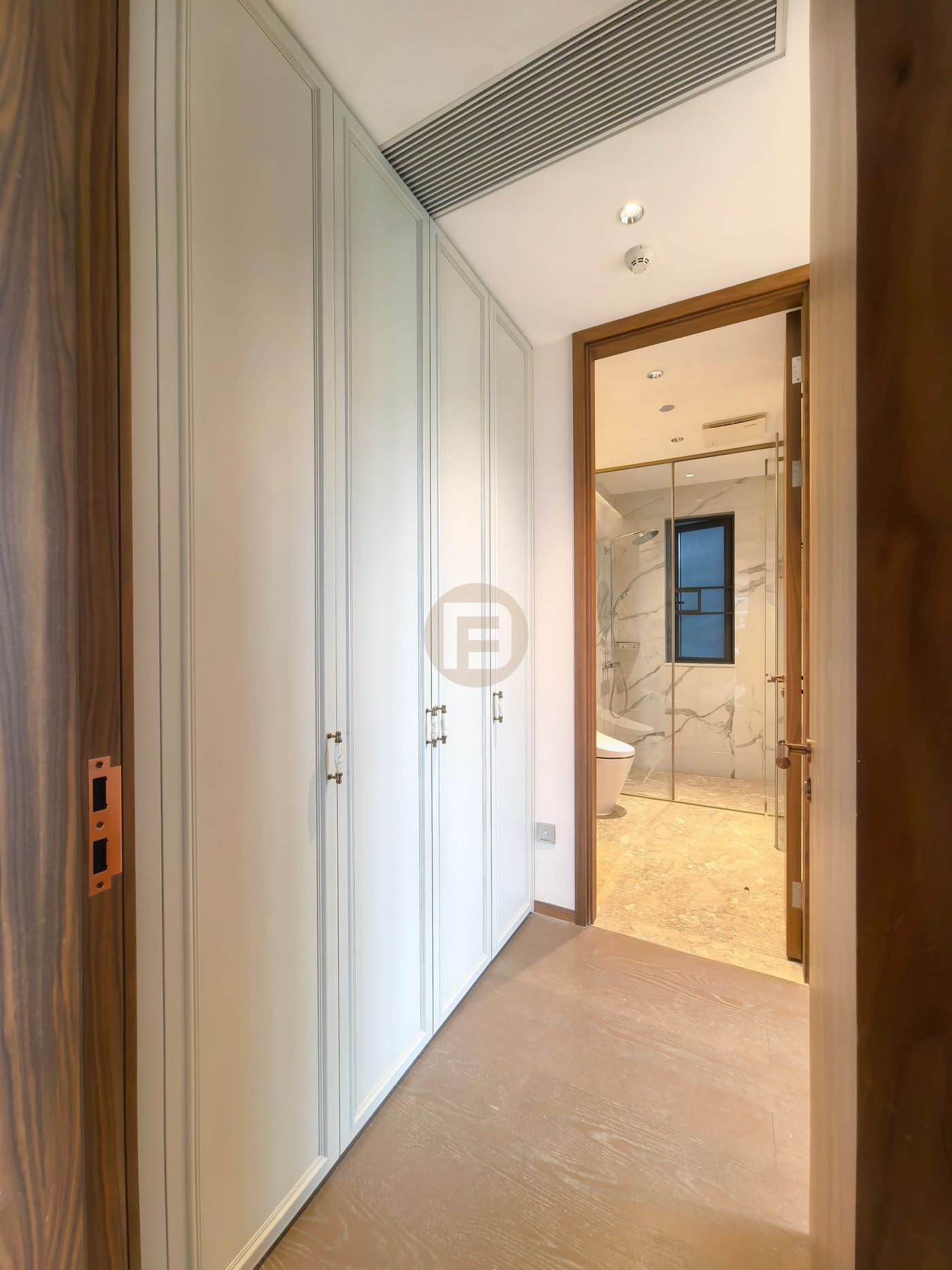 Wardrobe-lined corridor leading into a marble-clad bathroom