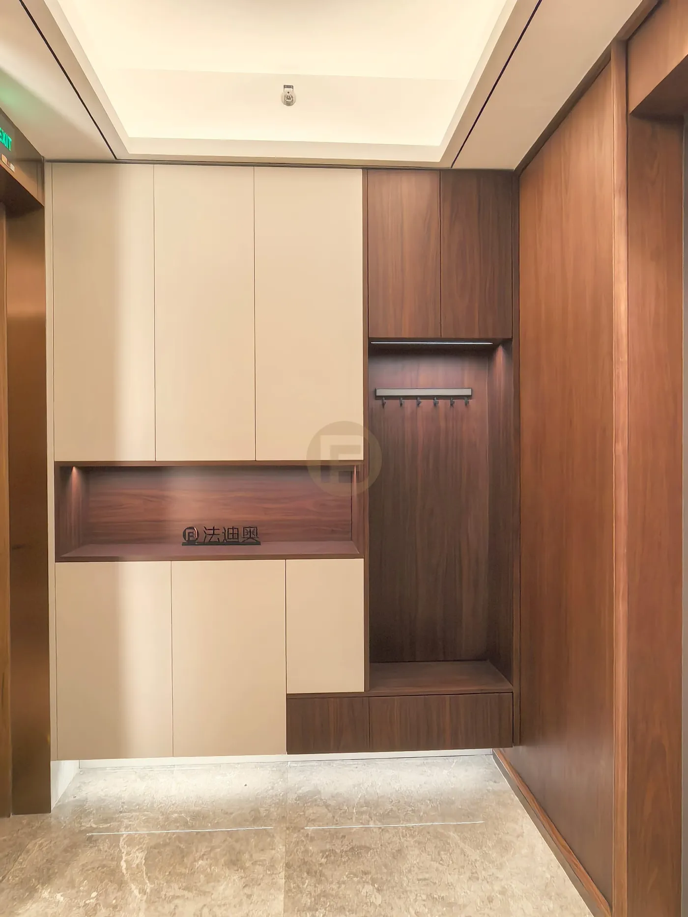 Cream and walnut entry cabinetry with coat hooks, bench seat and lit base plinth