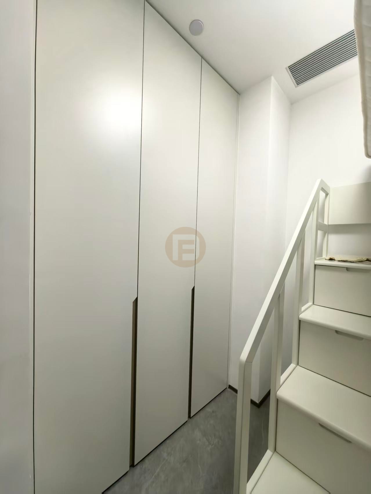Cream full-height stainless steel wardrobes fitted beside a white loft staircase