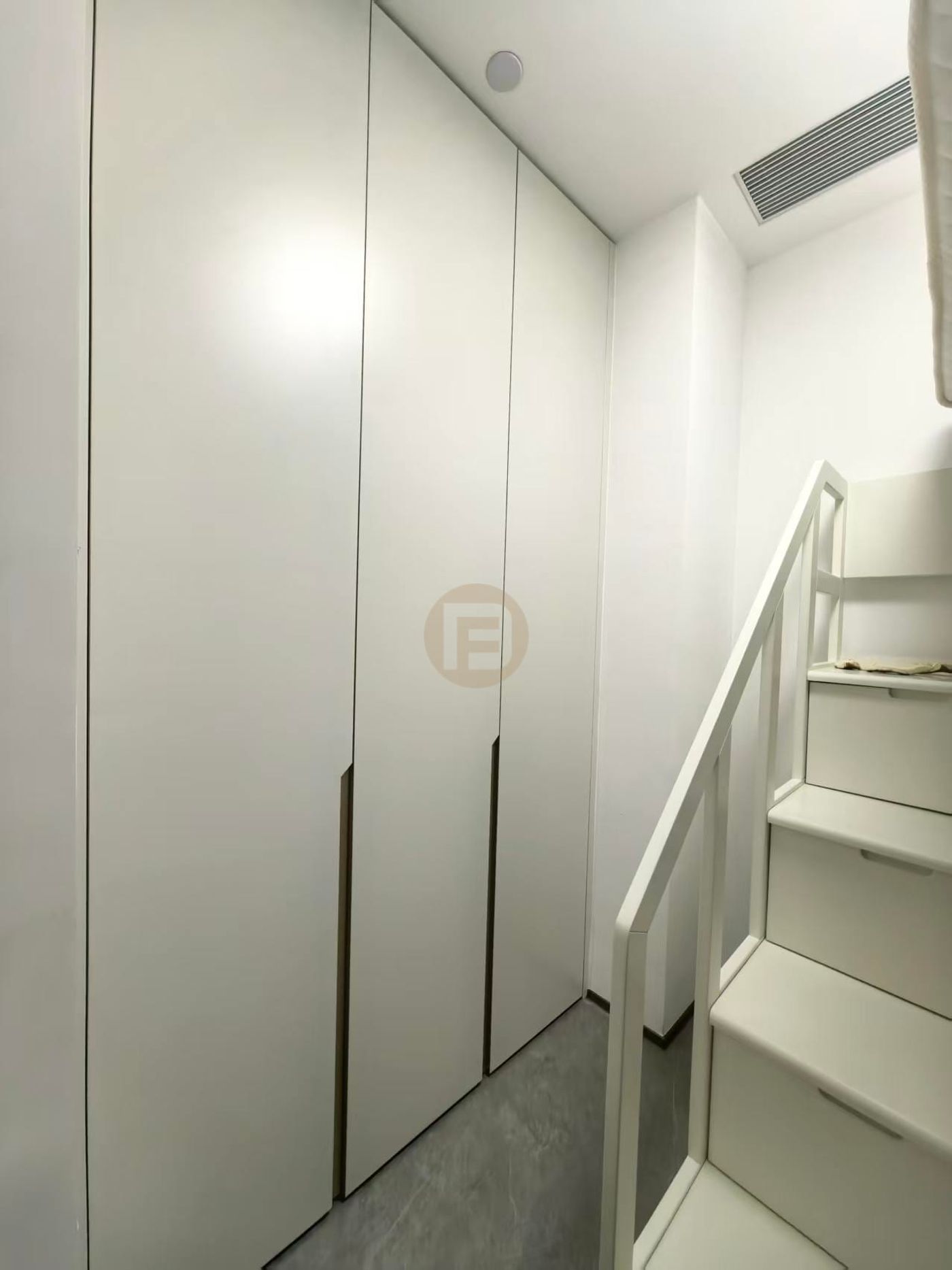 Cream full-height stainless steel wardrobes fitted beside a white loft staircase