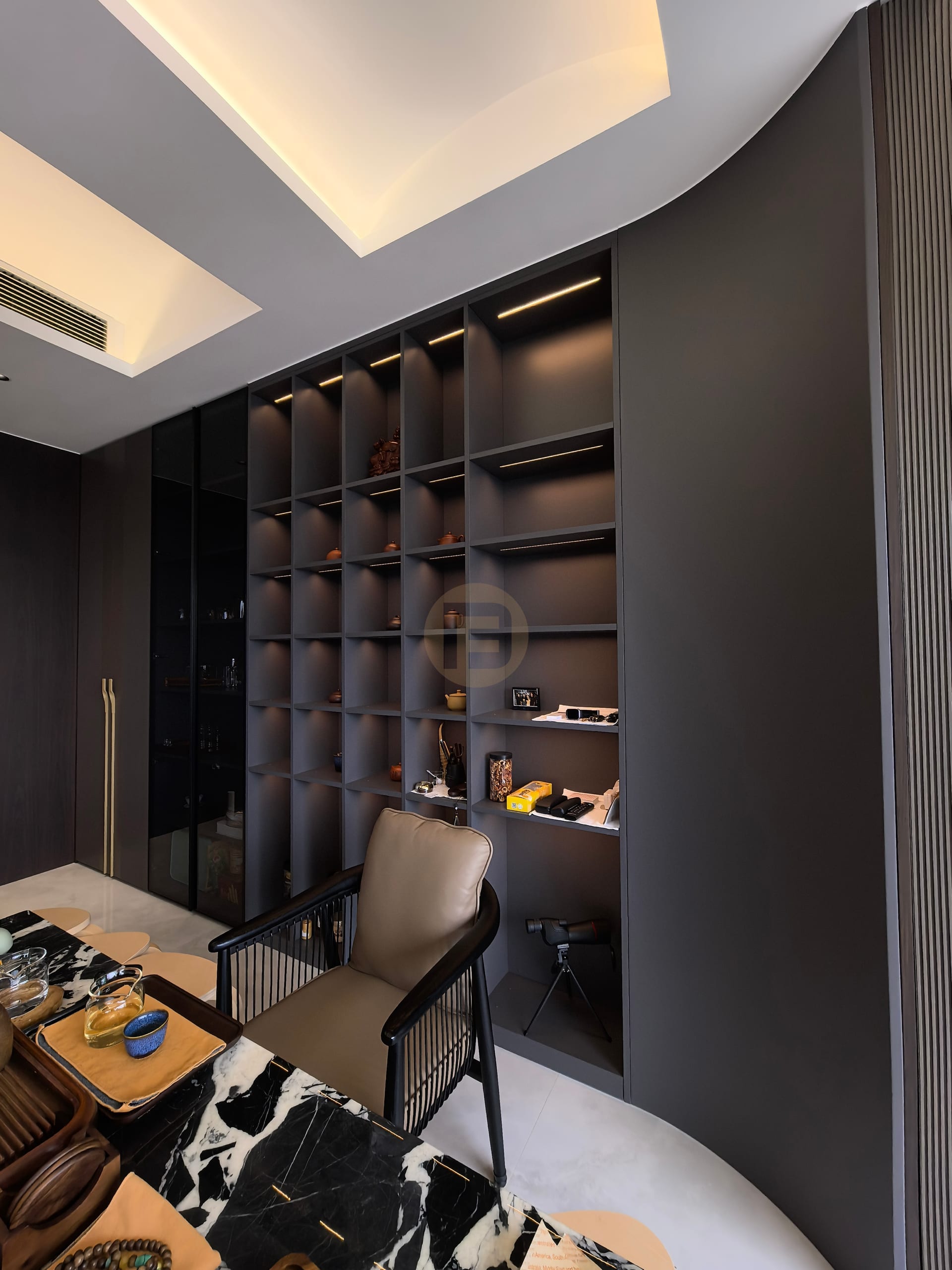 Charcoal display shelving with integrated lighting wraps the curved corner of the tea room