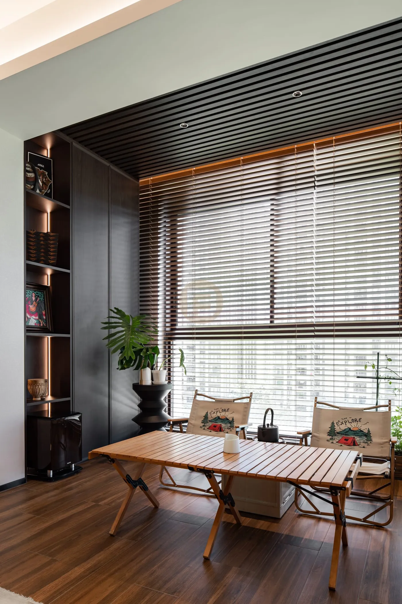 Balcony tea corner with dark full-height stainless steel cabinet, timber-slat ceiling and folding wood table