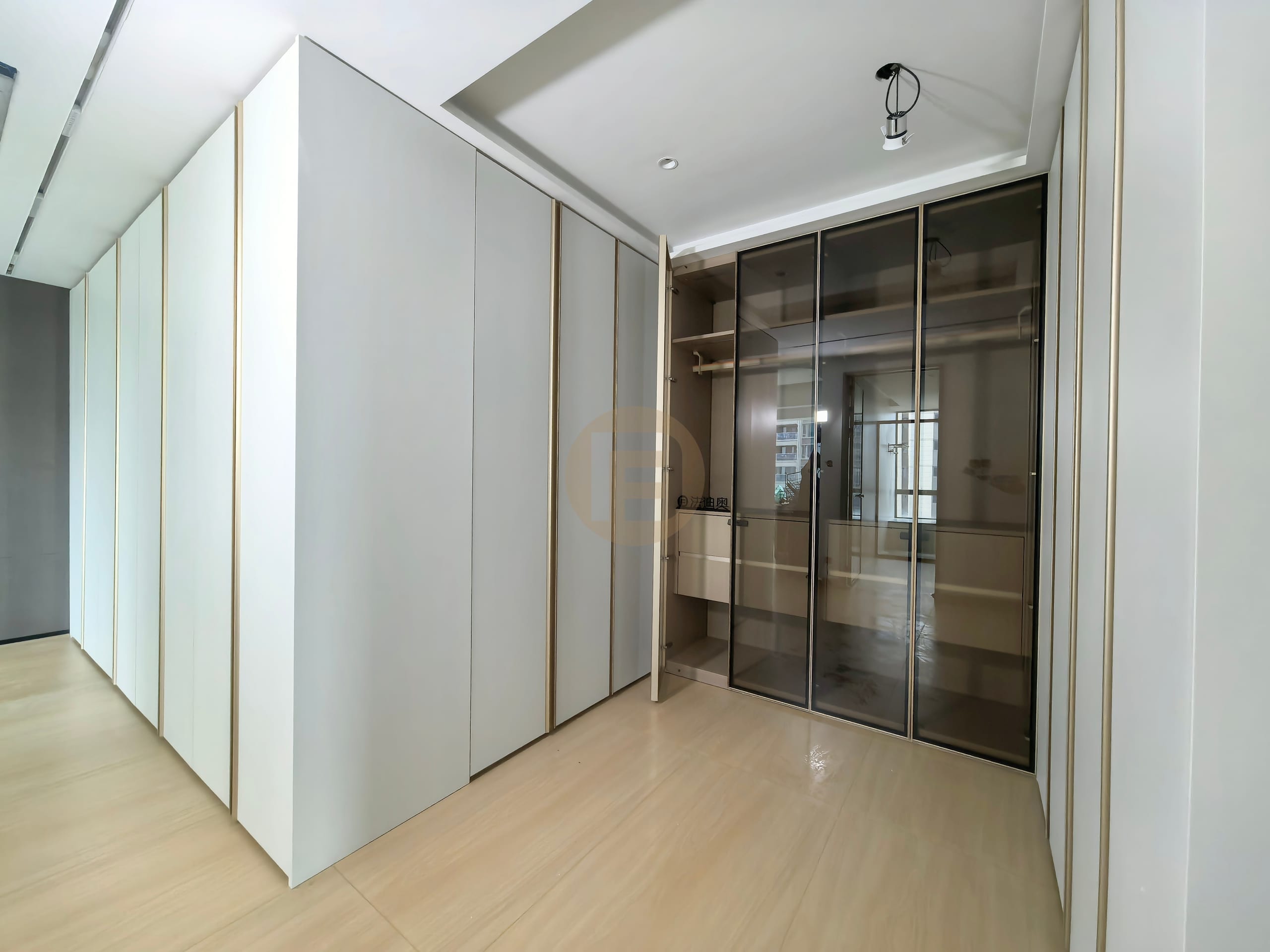 Walk-in dressing corridor with smoked bronze glass doors and pale grey lacquered stainless steel panels