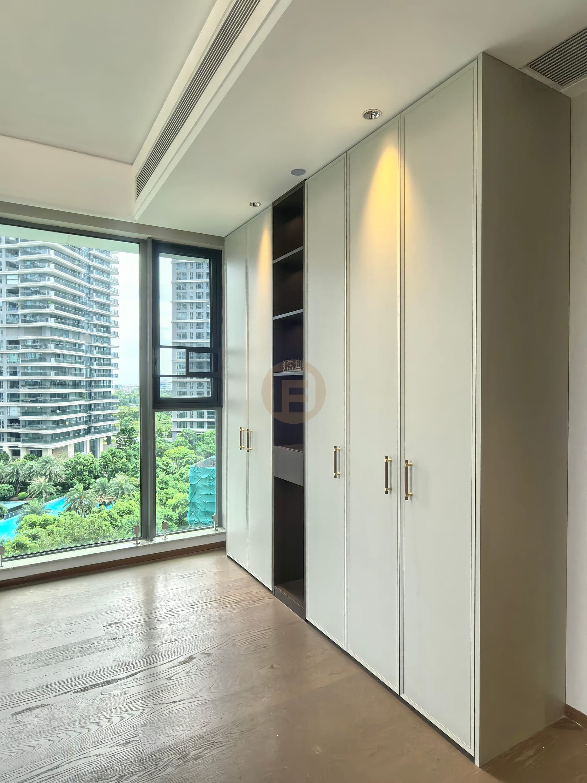 Full-height pale sage stainless steel wardrobes beside floor-to-ceiling windows with a park outlook