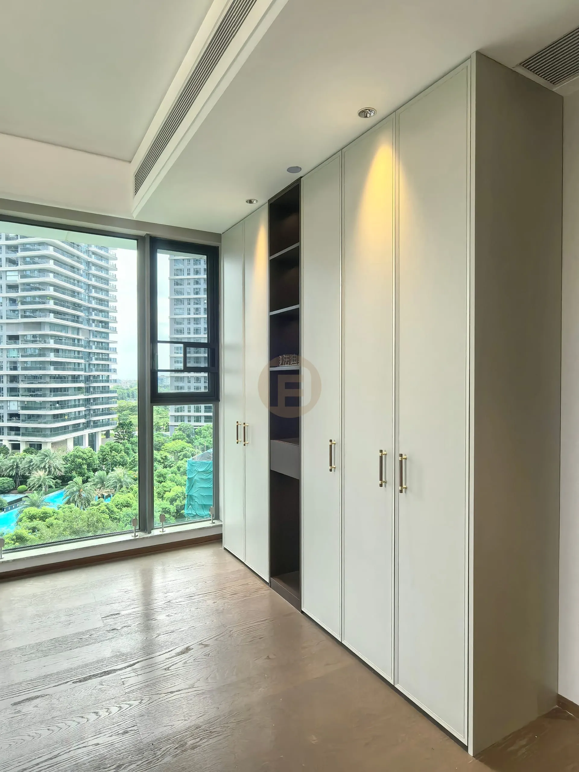 Full-height pale sage stainless steel wardrobes beside floor-to-ceiling windows with a park outlook