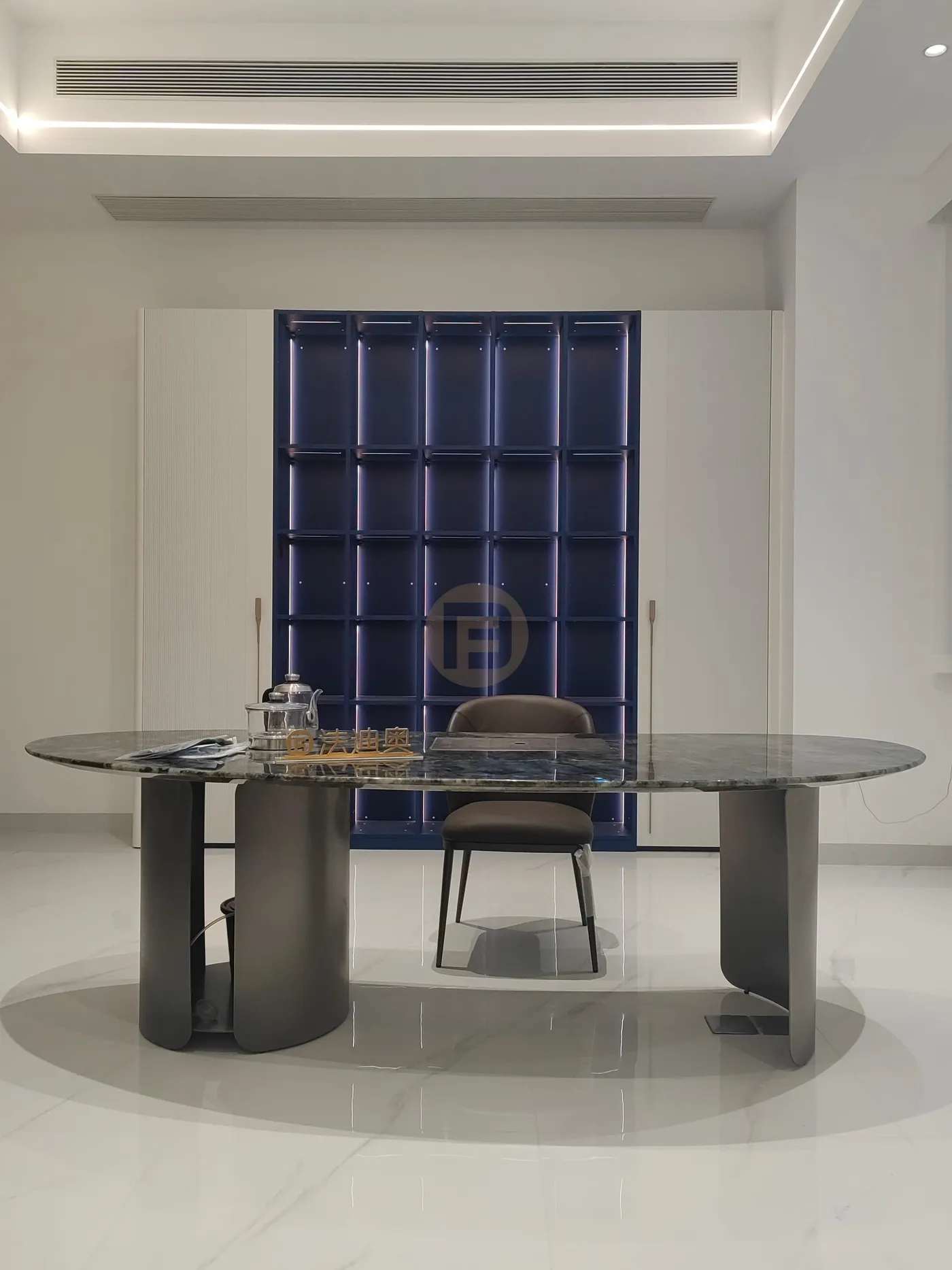 Study with green marble desk facing an illuminated navy display cabinet framed by white wardrobes