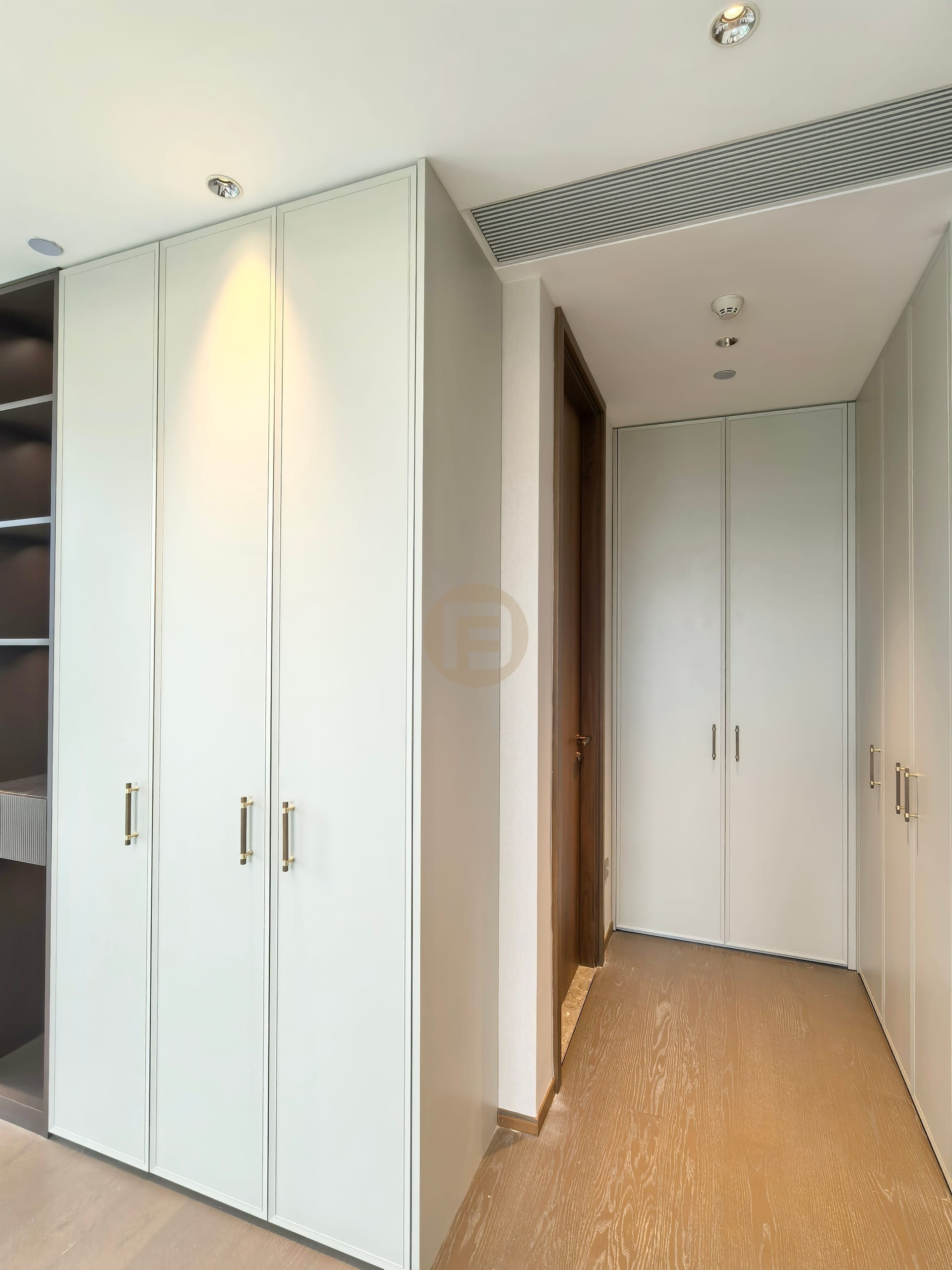 Dressing corridor lined on both sides with framed pale sage stainless steel wardrobes
