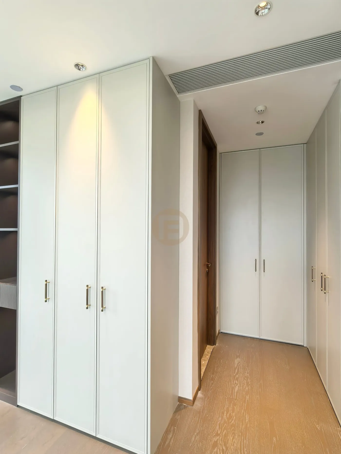 Dressing corridor lined on both sides with framed pale sage stainless steel wardrobes