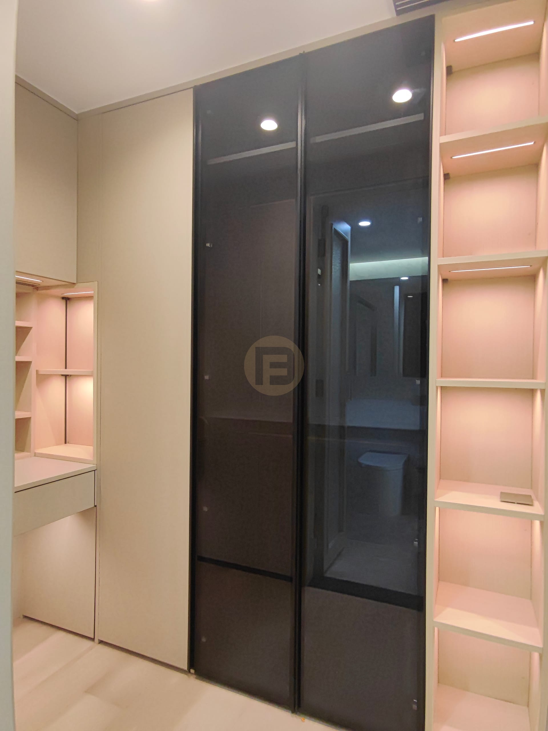 Dressing area with black glass stainless steel wardrobe doors and backlit cream shelving towers
