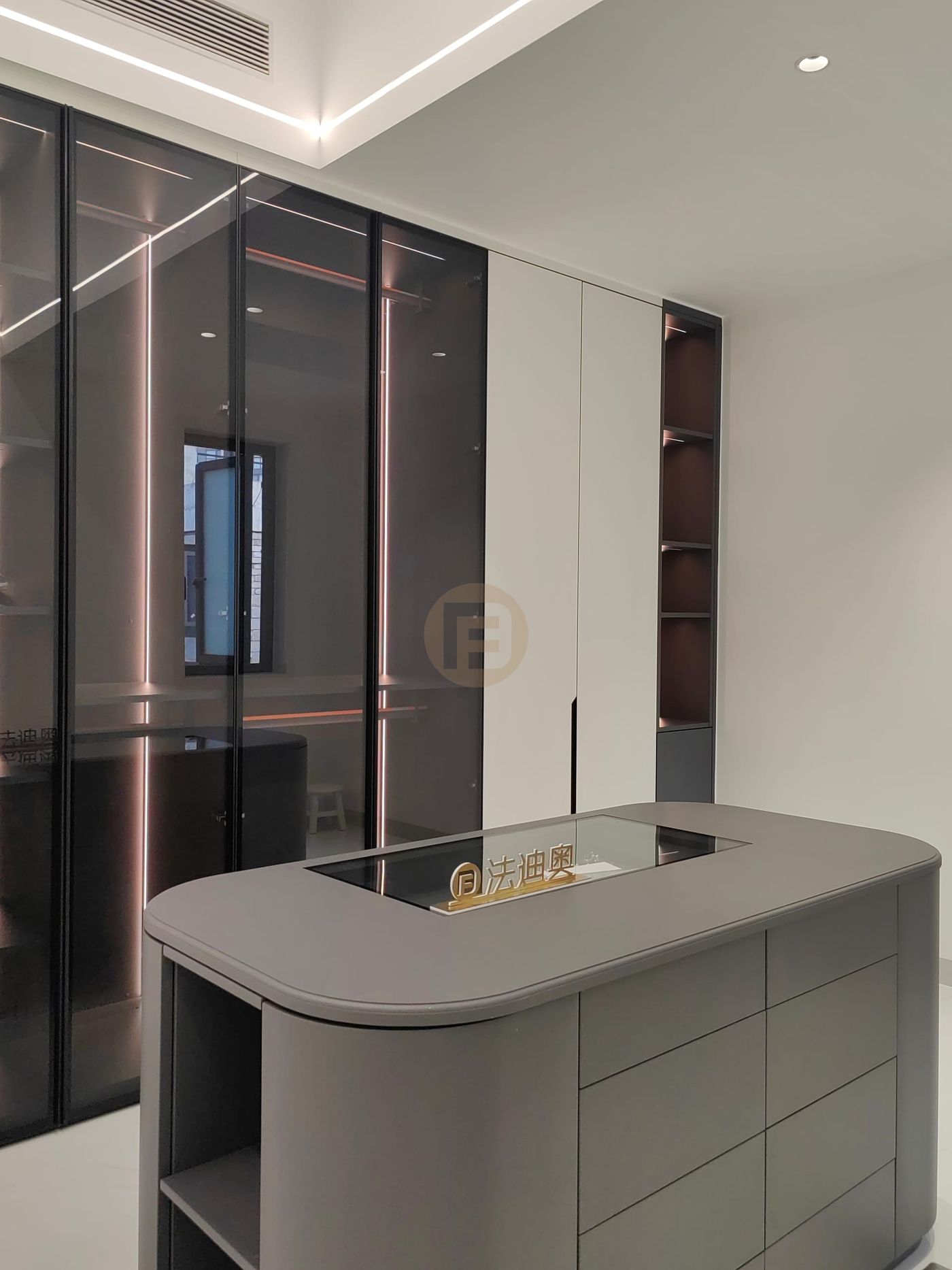 Walk-in closet with rounded grey island dresser and glass-front stainless steel wardrobes