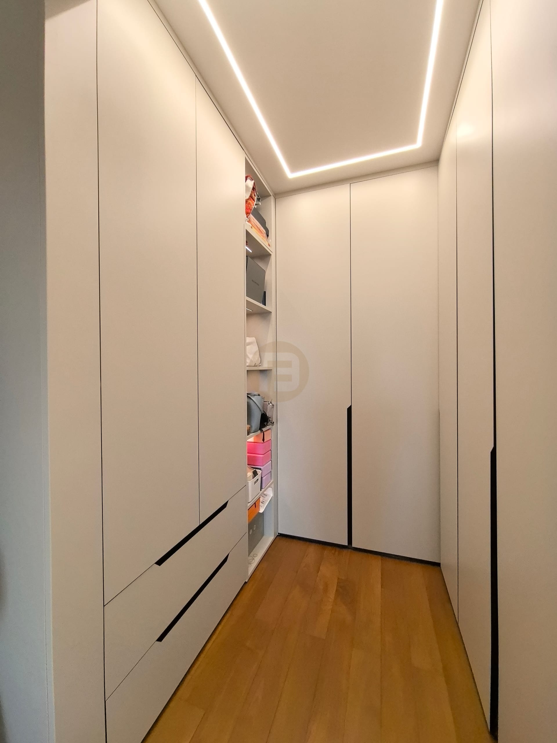 Walk-in closet lined with matte white stainless steel wardrobes under a recessed LED ceiling frame