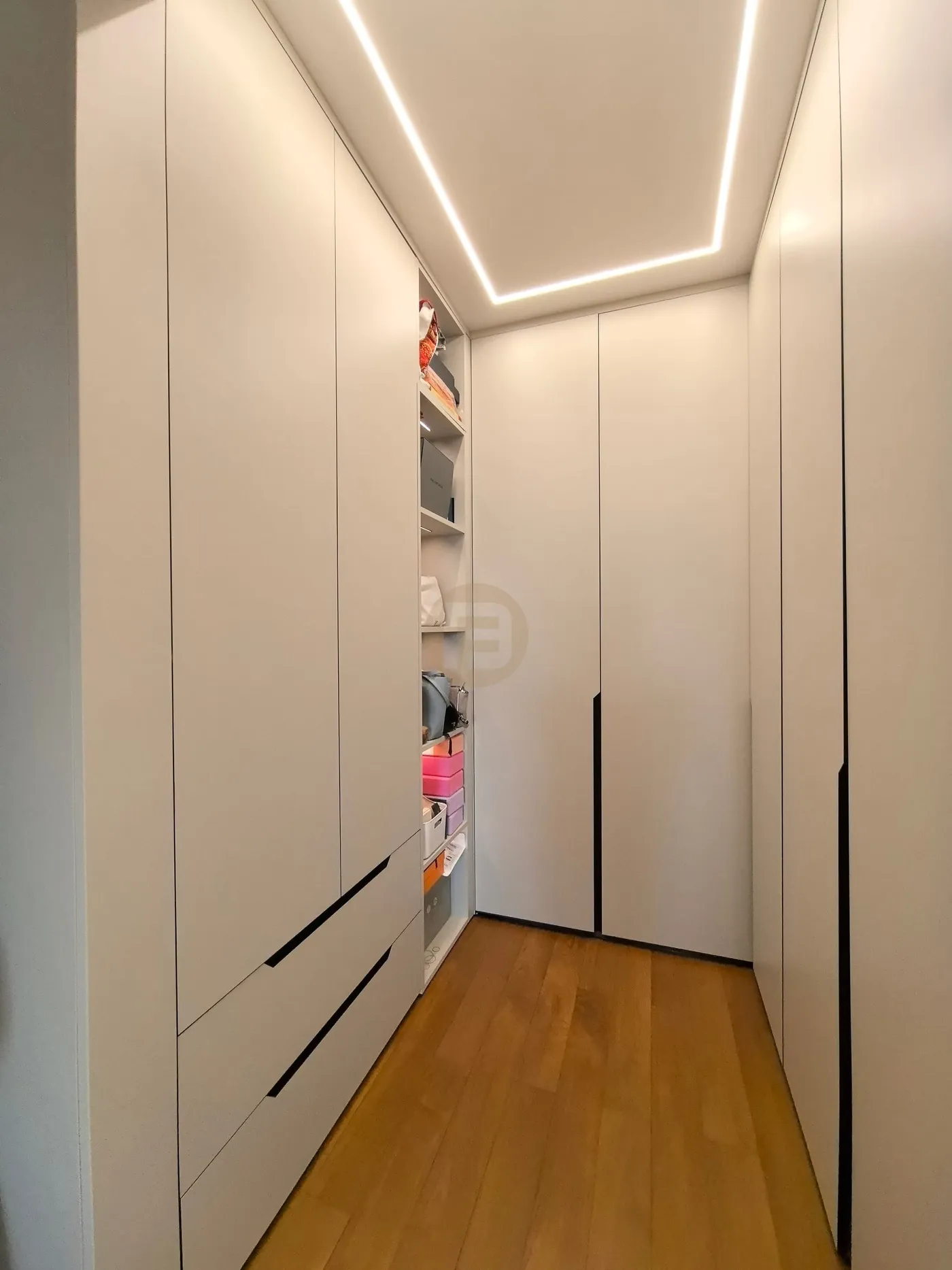Walk-in closet lined with matte white stainless steel wardrobes under a recessed LED ceiling frame