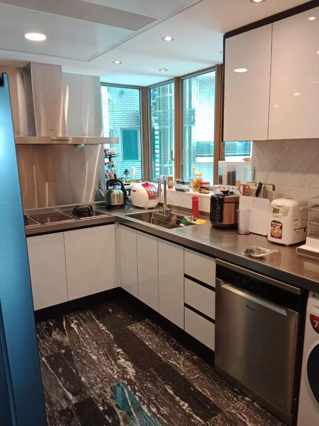 Compact kitchen with gloss white stainless steel cabinetry, steel worktops and a windowed corner