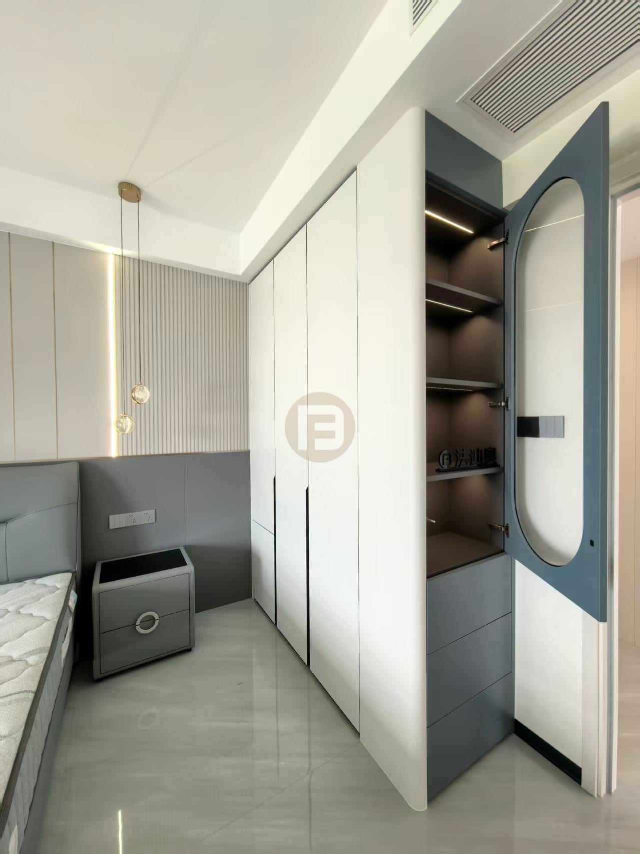 White stainless steel wardrobes with an open blue-grey display column beside the bed in the primary bedroom
