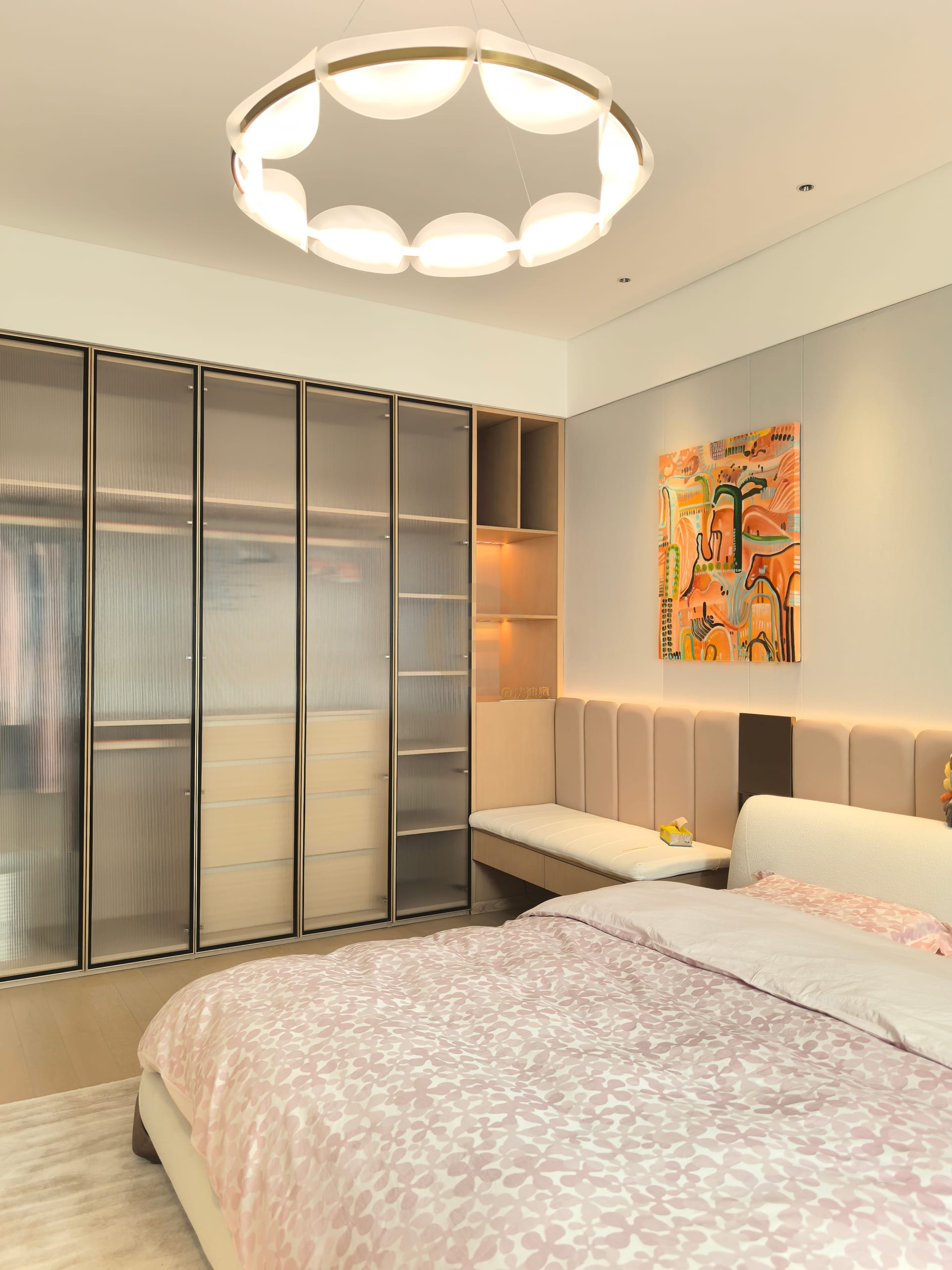 Bronze-framed reeded-glass wardrobe wall beside an upholstered bench in the primary bedroom