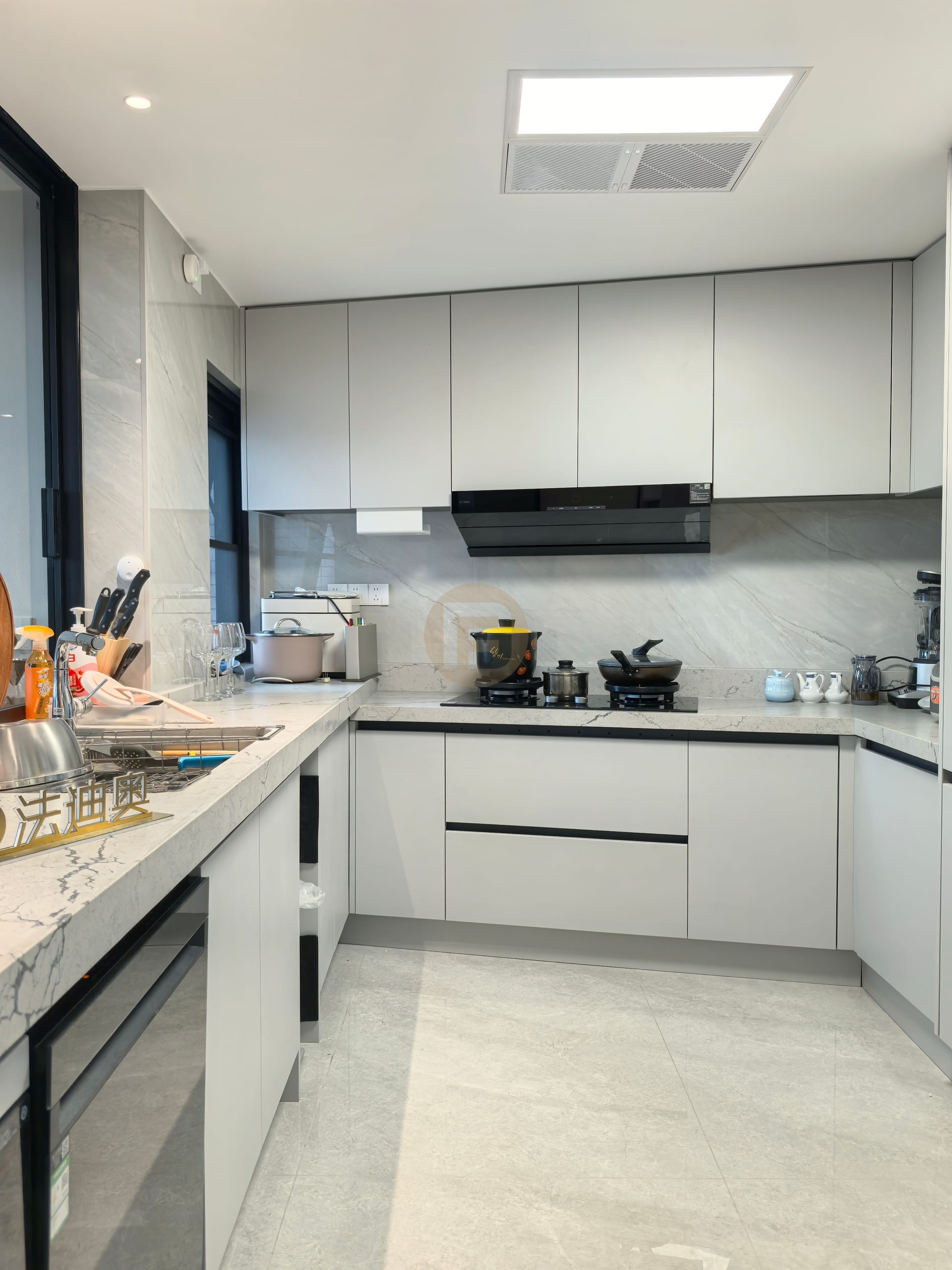 Cooking zone with light grey stainless steel cabinets, black extractor and marble backsplash