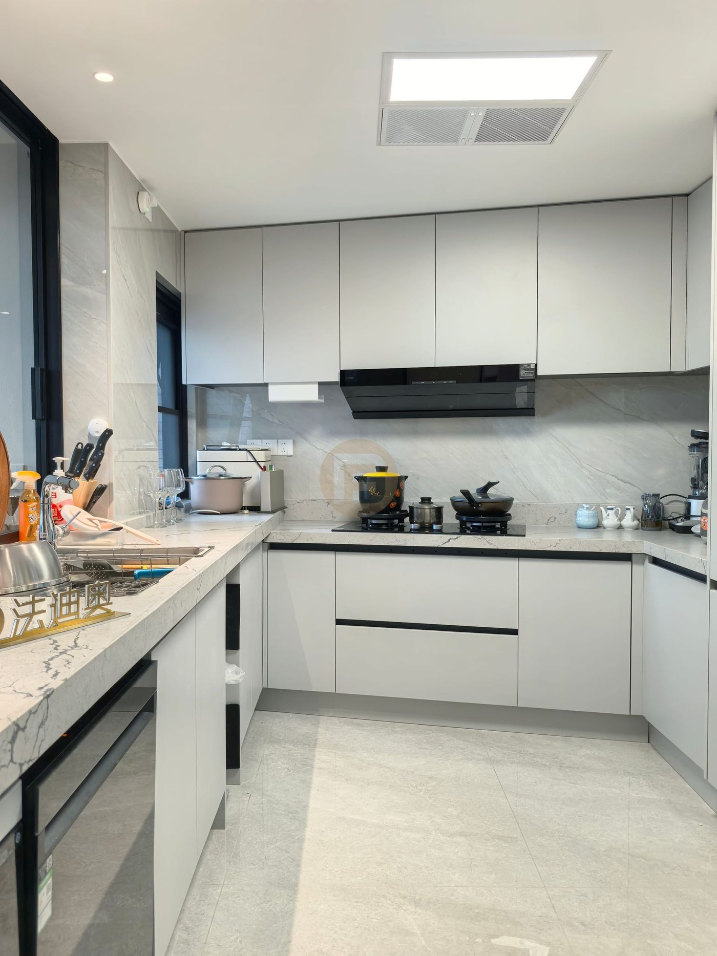 Cooking zone with light grey stainless steel cabinets, black extractor and marble backsplash