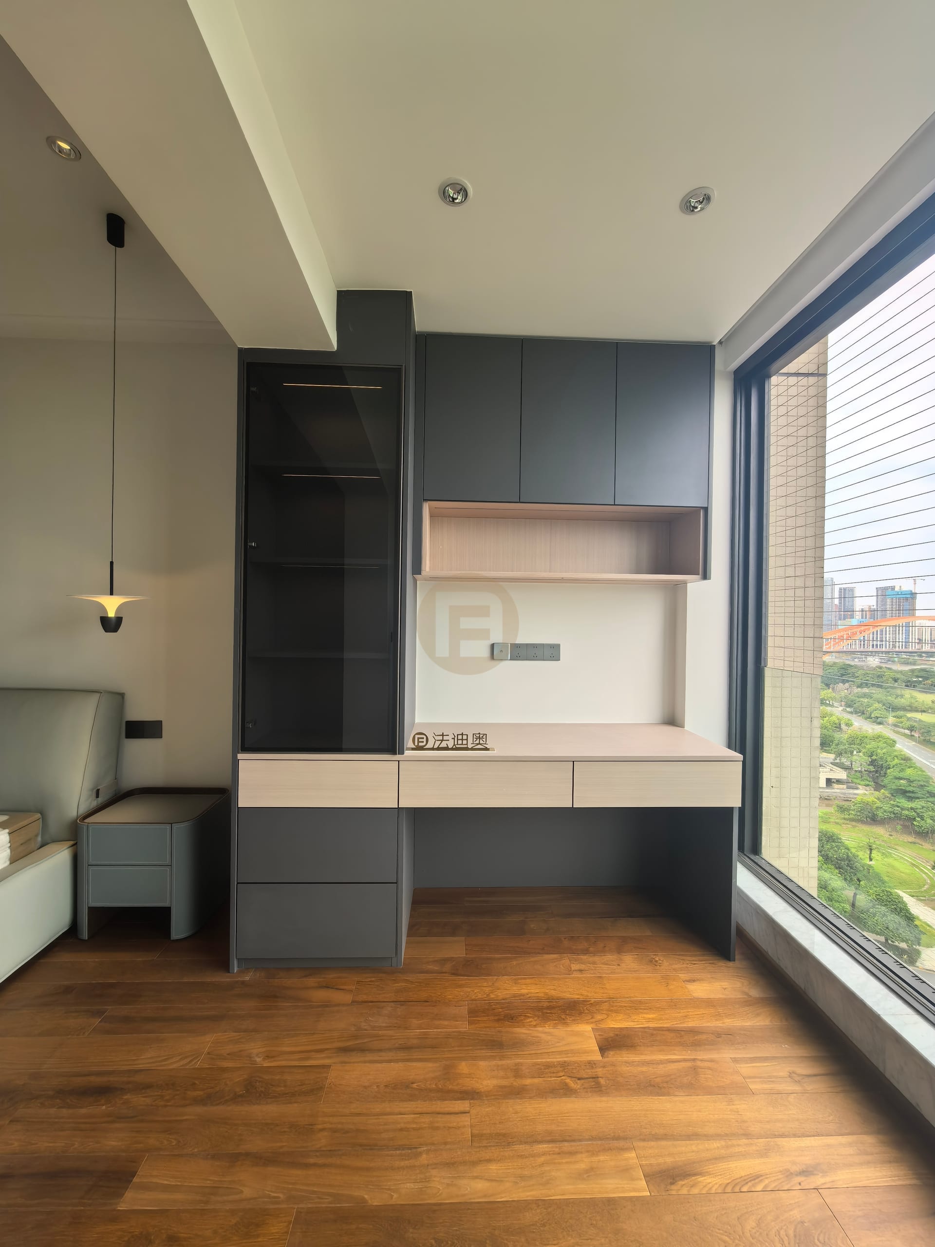 Built-in desk with wood-grain top, dark grey wall cabinets and a glazed display tower by the window