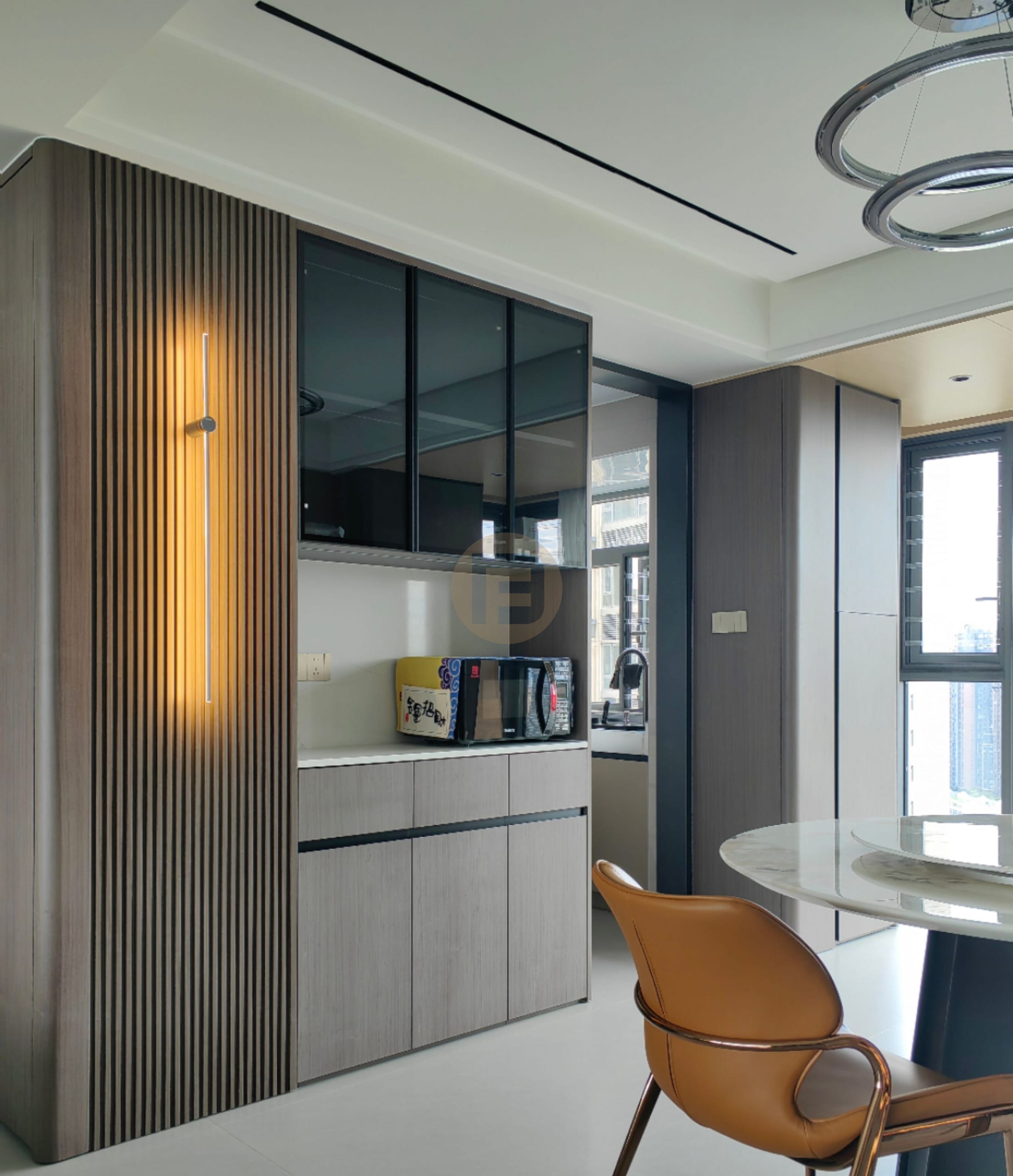 Dark wood-grain stainless steel sideboard with lit fluted panel and smoked-glass cabinets beside a round marble dining table
