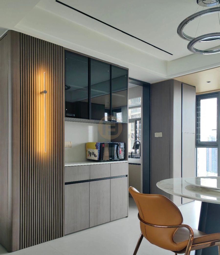 Dark wood-grain stainless steel sideboard with lit fluted panel and smoked-glass cabinets beside a round marble dining table