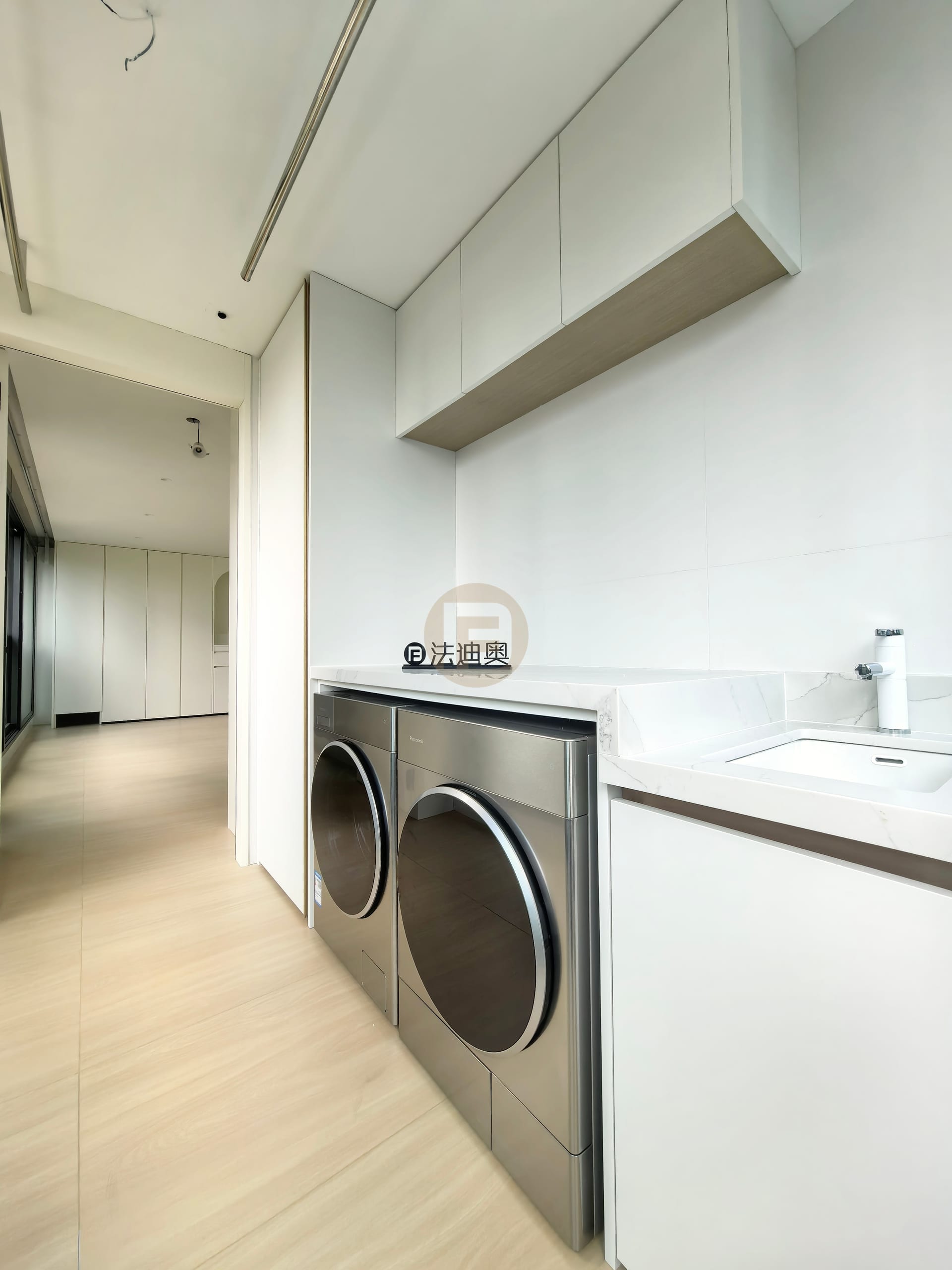 Laundry balcony with overhead white cabinets, stone counter, inset sink and stainless-faced machines
