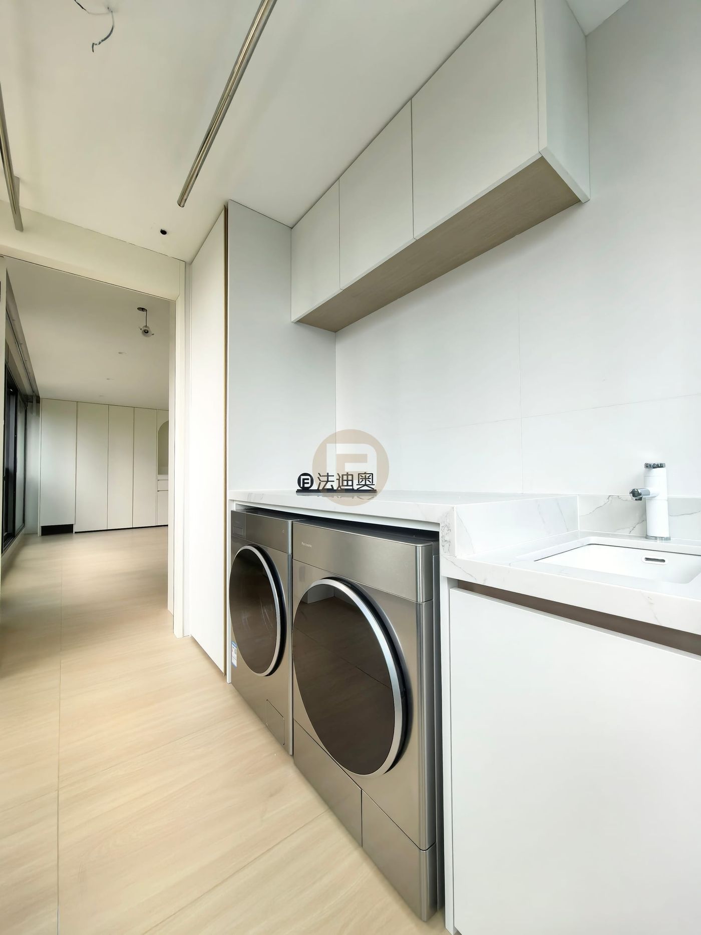 Laundry balcony with overhead white cabinets, stone counter, inset sink and stainless-faced machines
