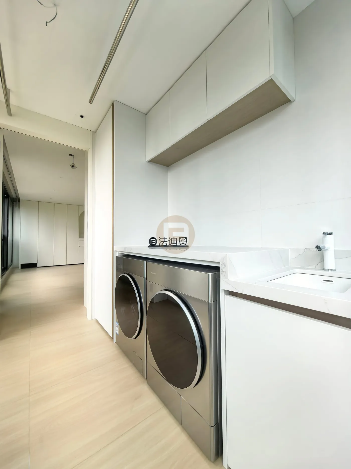 Laundry balcony with overhead white cabinets, stone counter, inset sink and stainless-faced machines