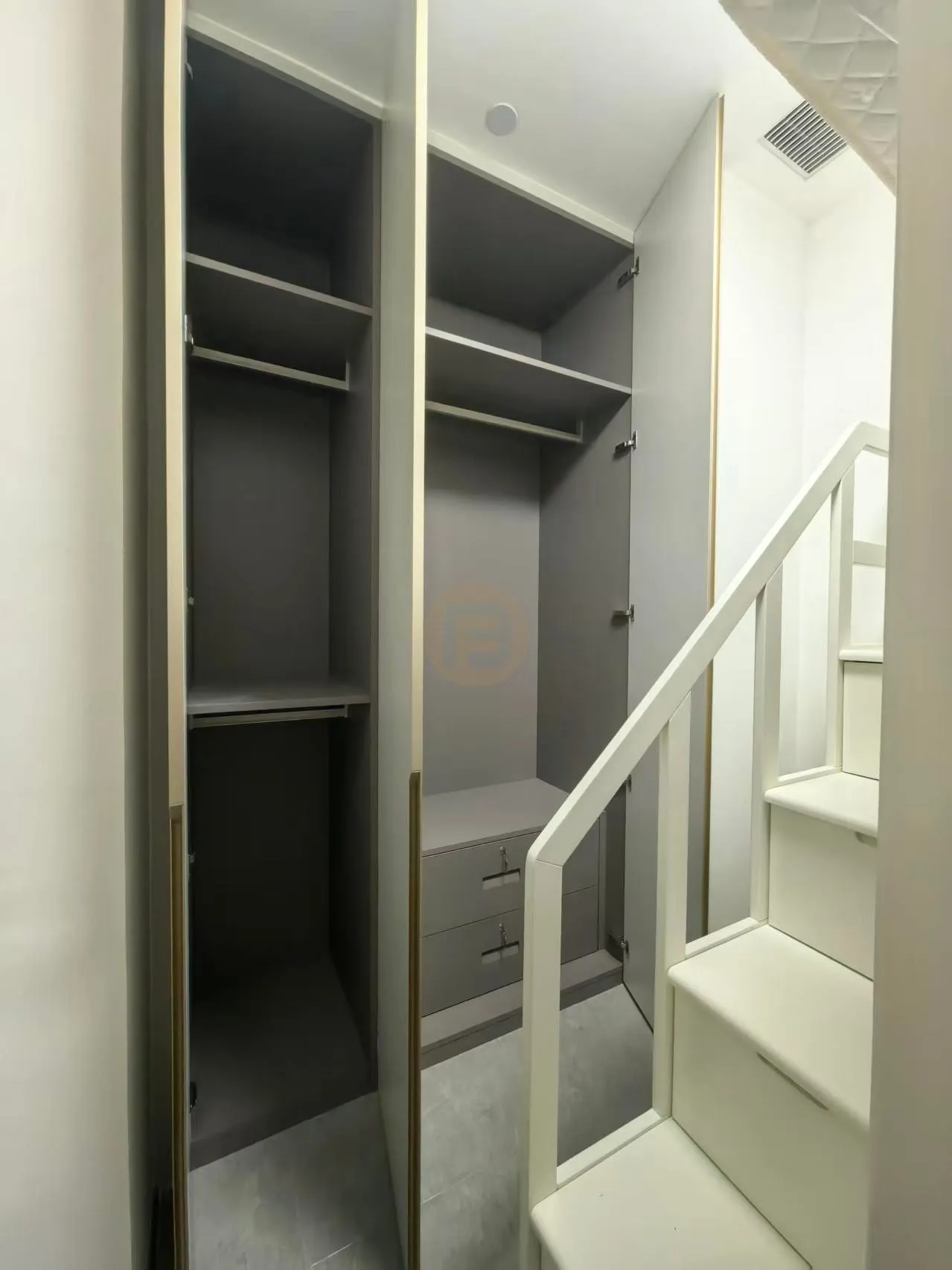 Open wardrobe bay in warm grey stainless steel with shelves, hanging rails and integrated drawers