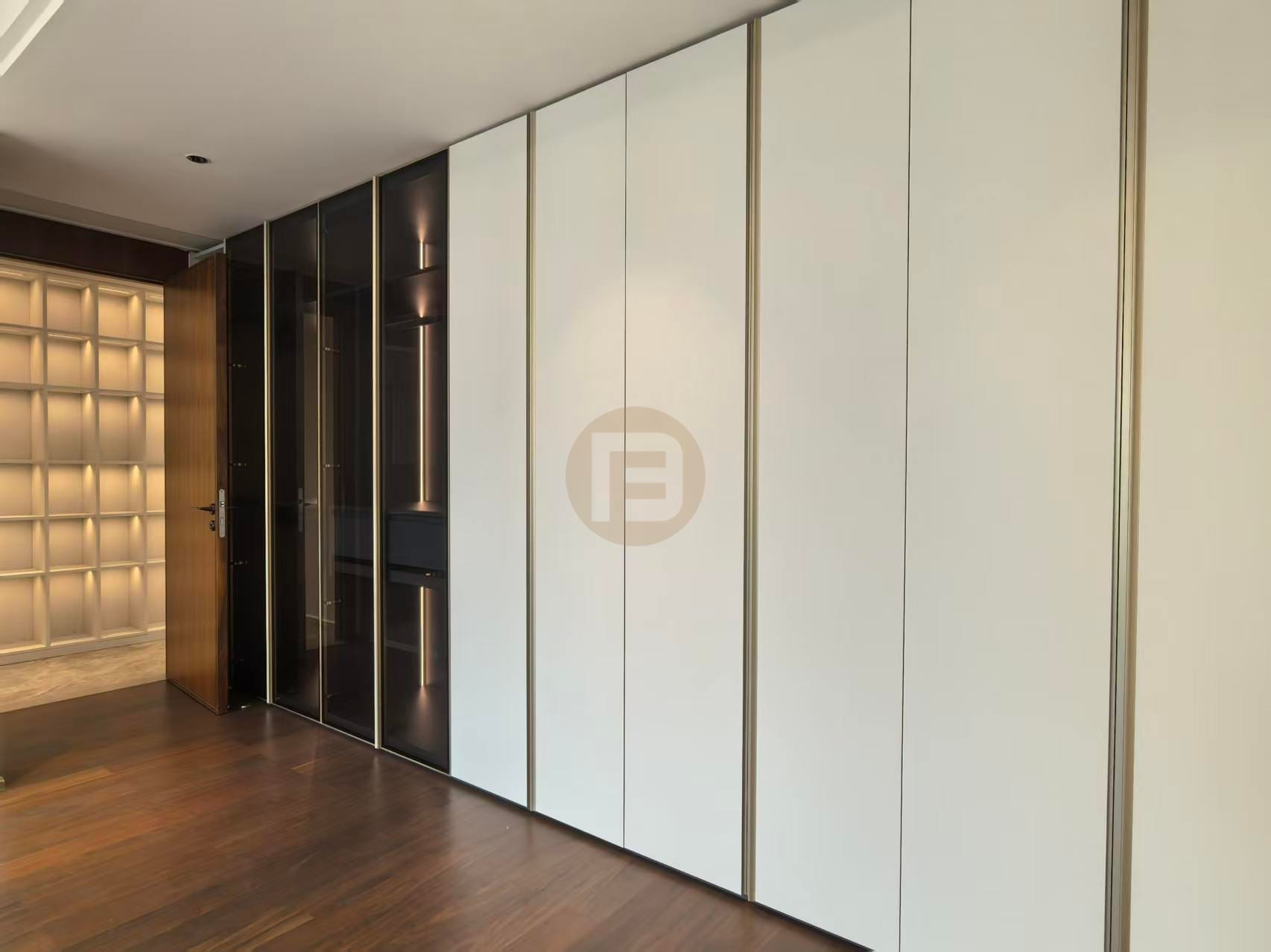 Full-height white stainless steel wardrobe wall with bronze trims and a smoked-glass display section