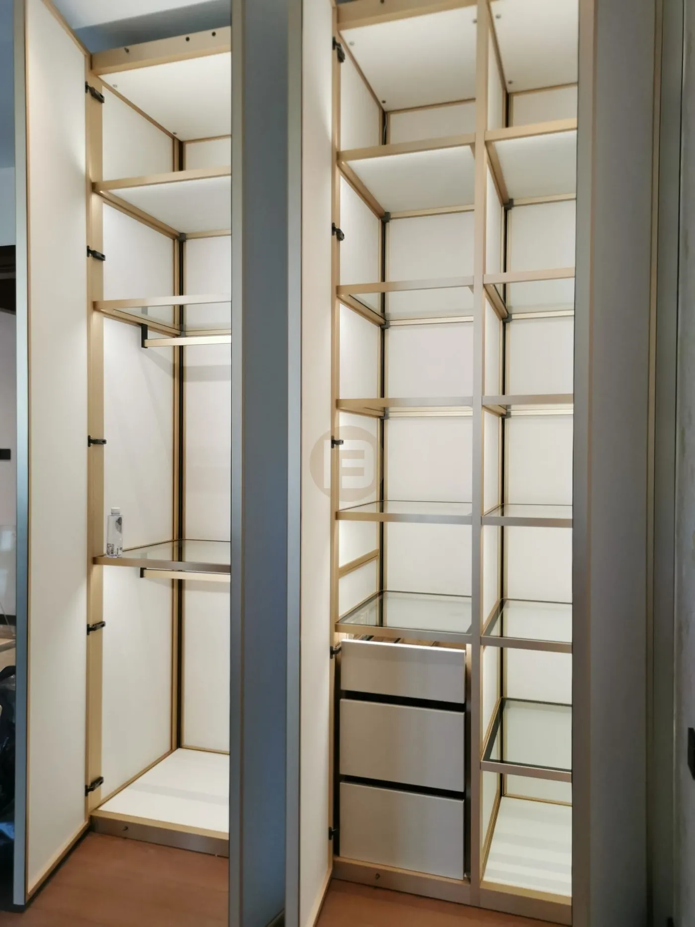 Open stainless steel wardrobe columns with champagne-gold framing, glass shelves and hanging rails