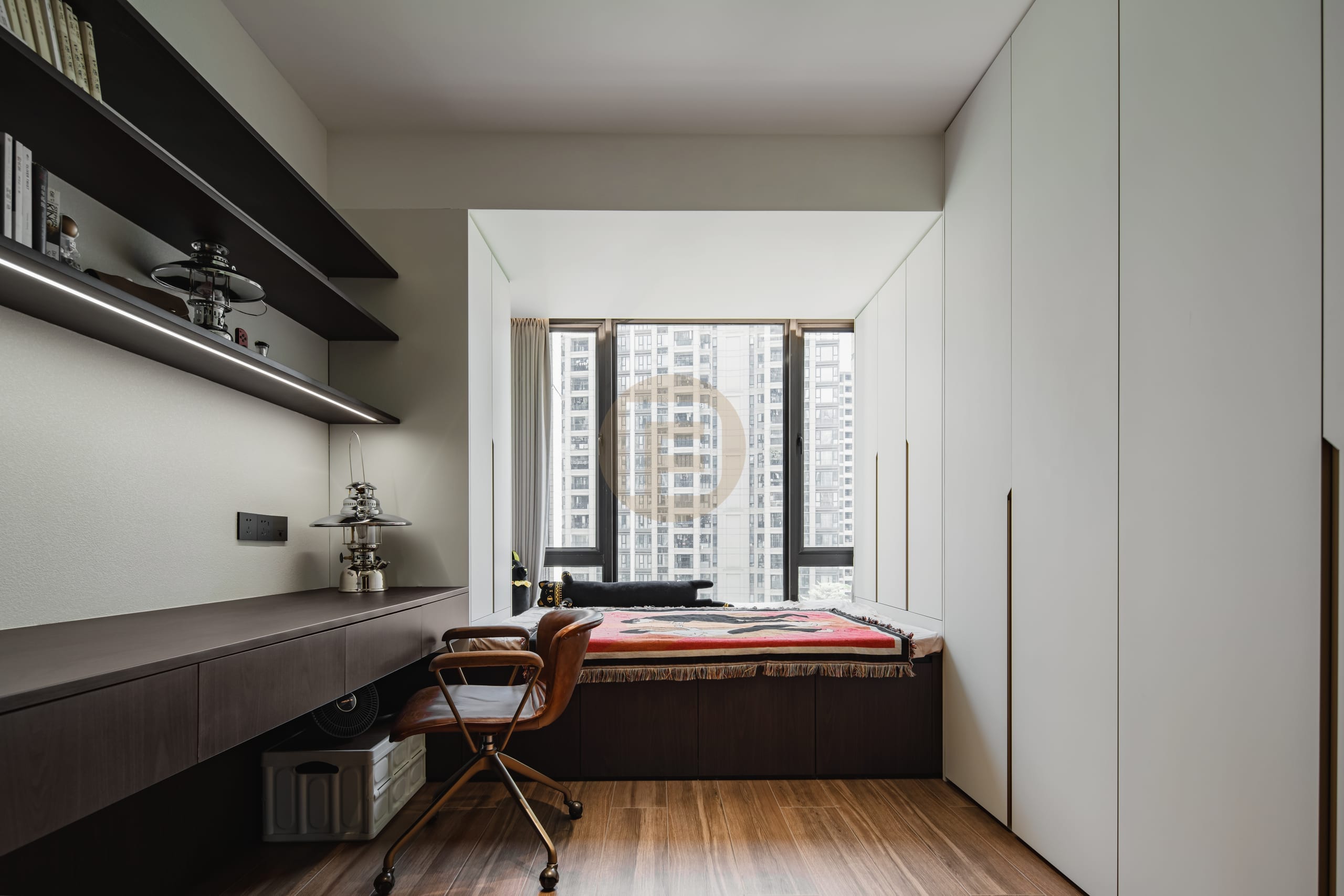 Study with floating dark desk and shelving opposite a cream stainless steel wardrobe and window daybed